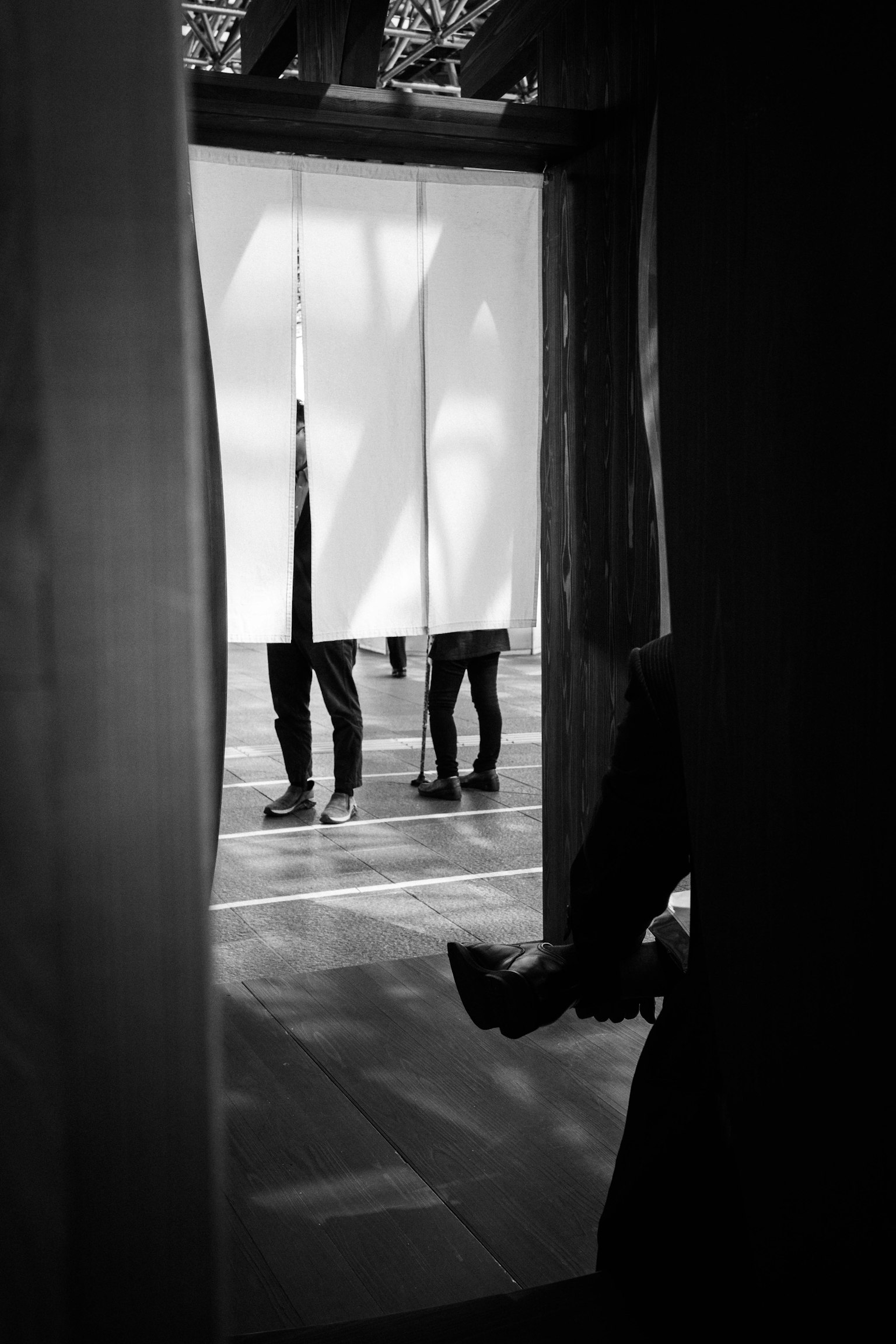 Siluetas de personas de pie detrás de una cortina blanca en una imagen en blanco y negro