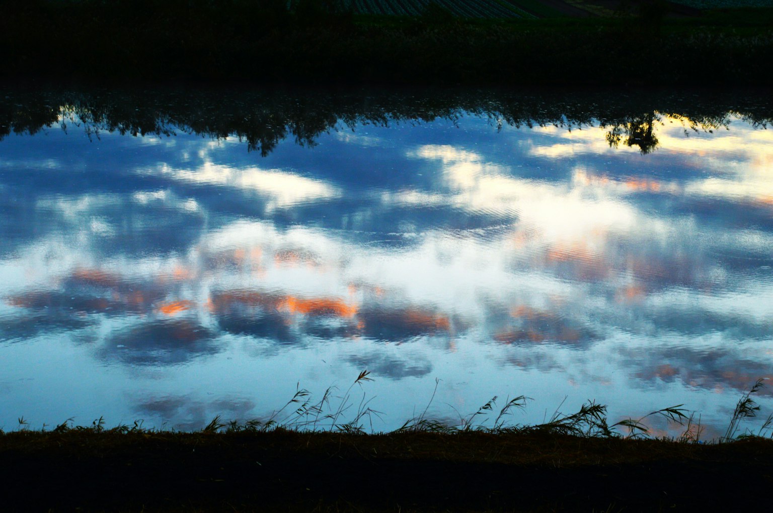 Bella riflessione di nuvole e cielo su una superficie d'acqua calma