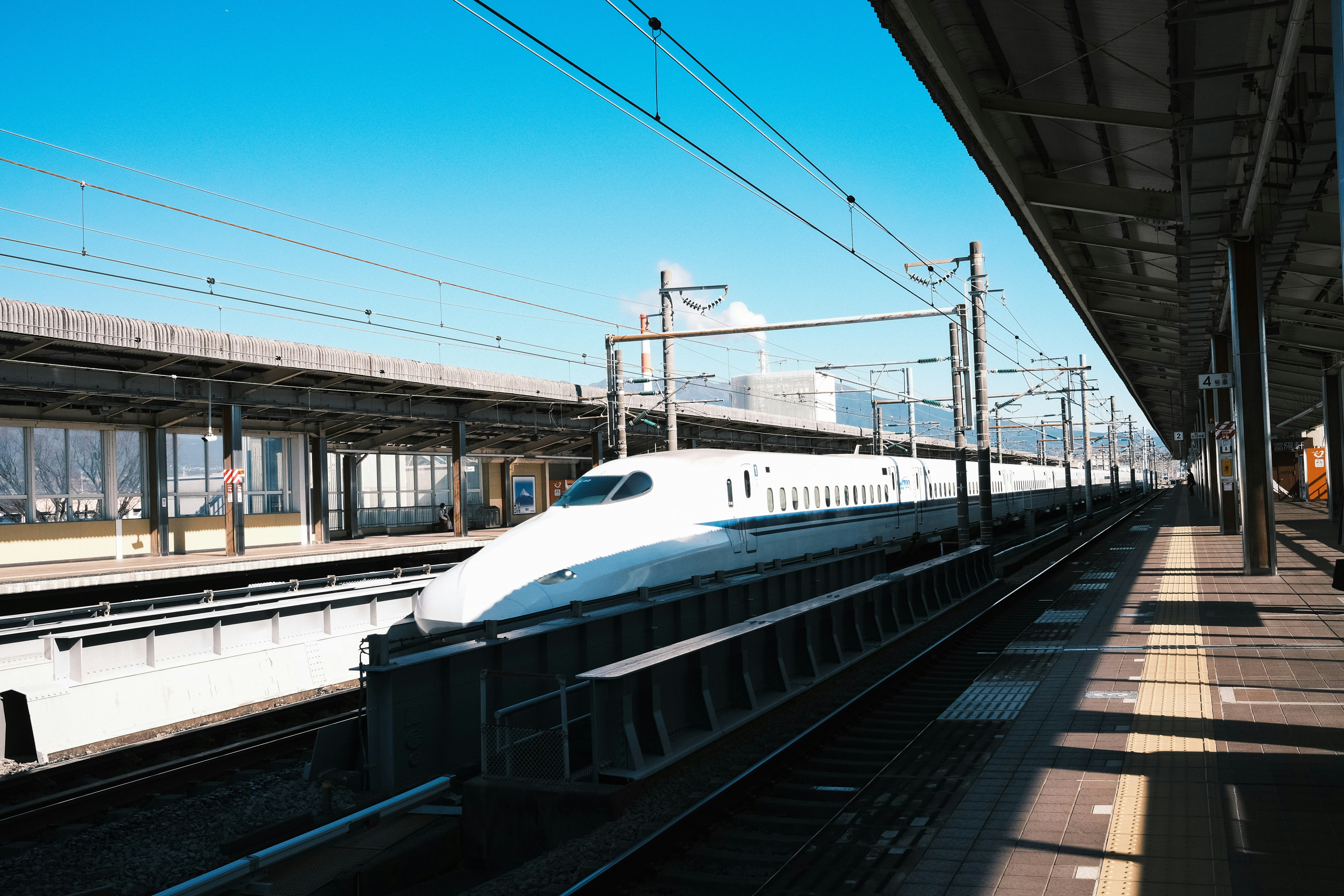 駅ホームを走る白い新幹線