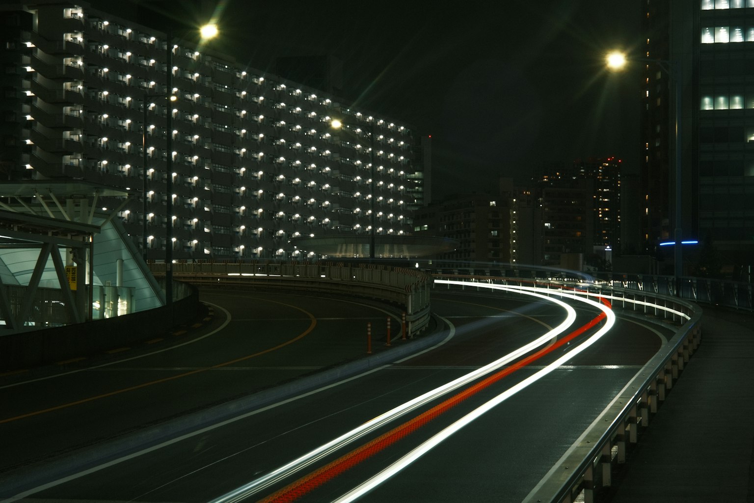 Paysage urbain nocturne avec une route sinueuse et des traînées de lumière de voiture