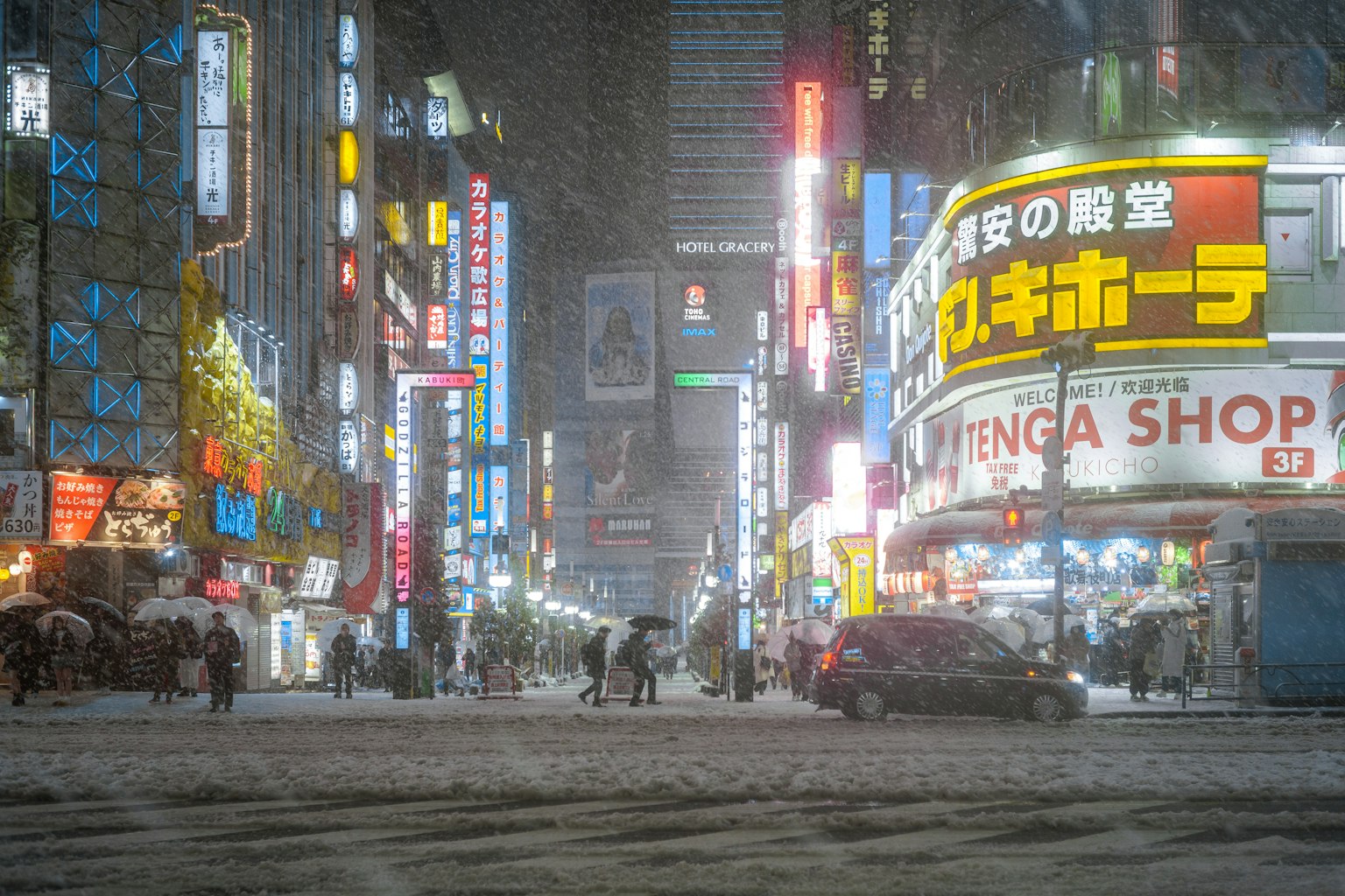 Jalan bersalju di Shinjuku di malam hari dengan lampu neon yang cerah dan pejalan kaki