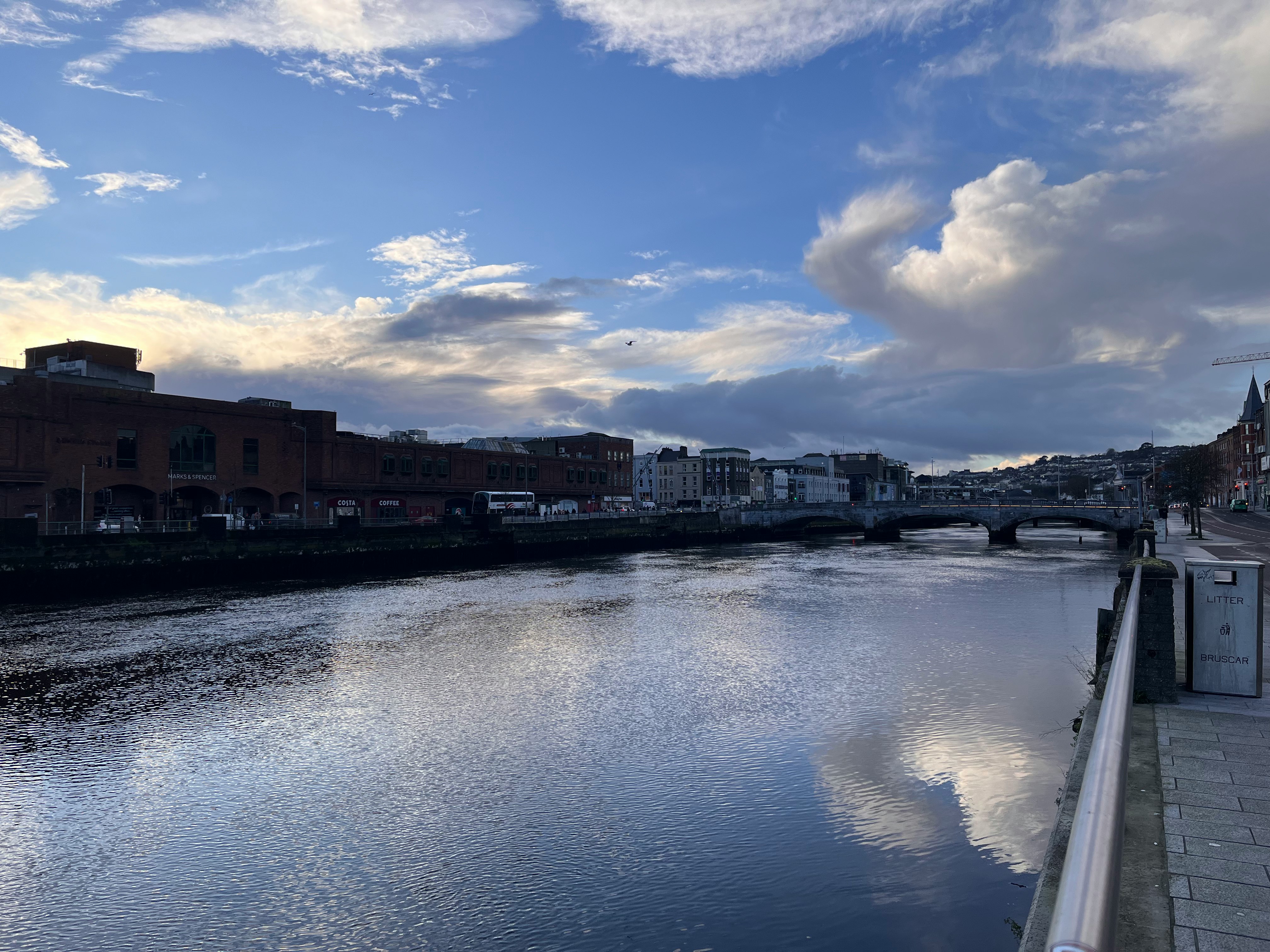 riverside promenade with city skyline and calm water reflections