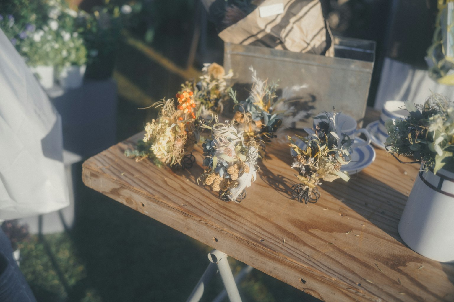 木製テーブルの上に置かれたドライフラワーの束と植物の鉢