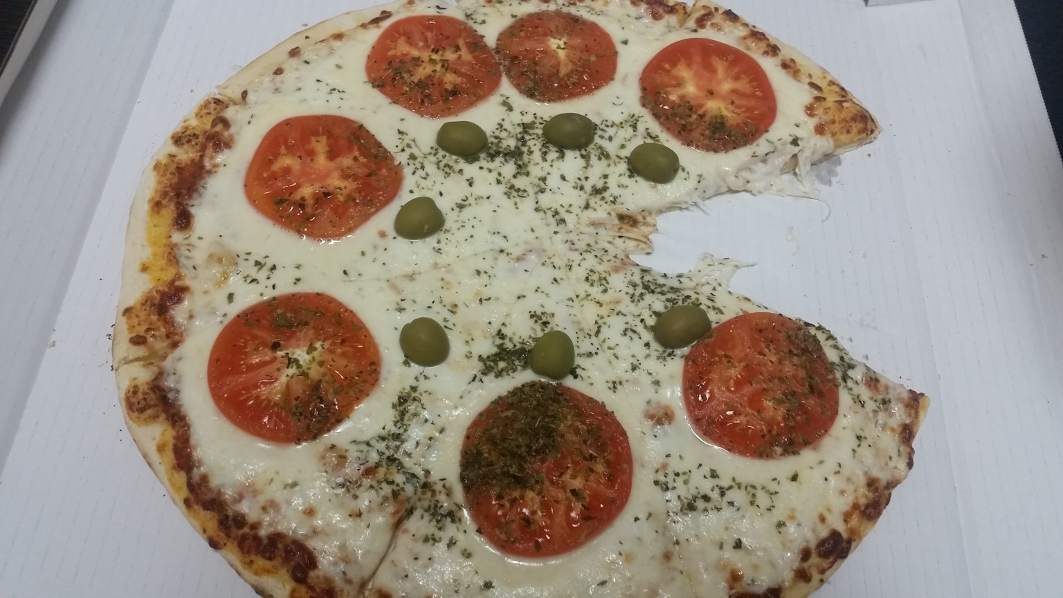 Pizza con pomodori e olive con una fetta mancante