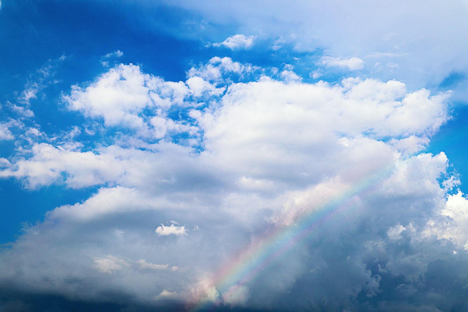 一道彩虹橫跨明亮的藍天和蓬鬆的白雲