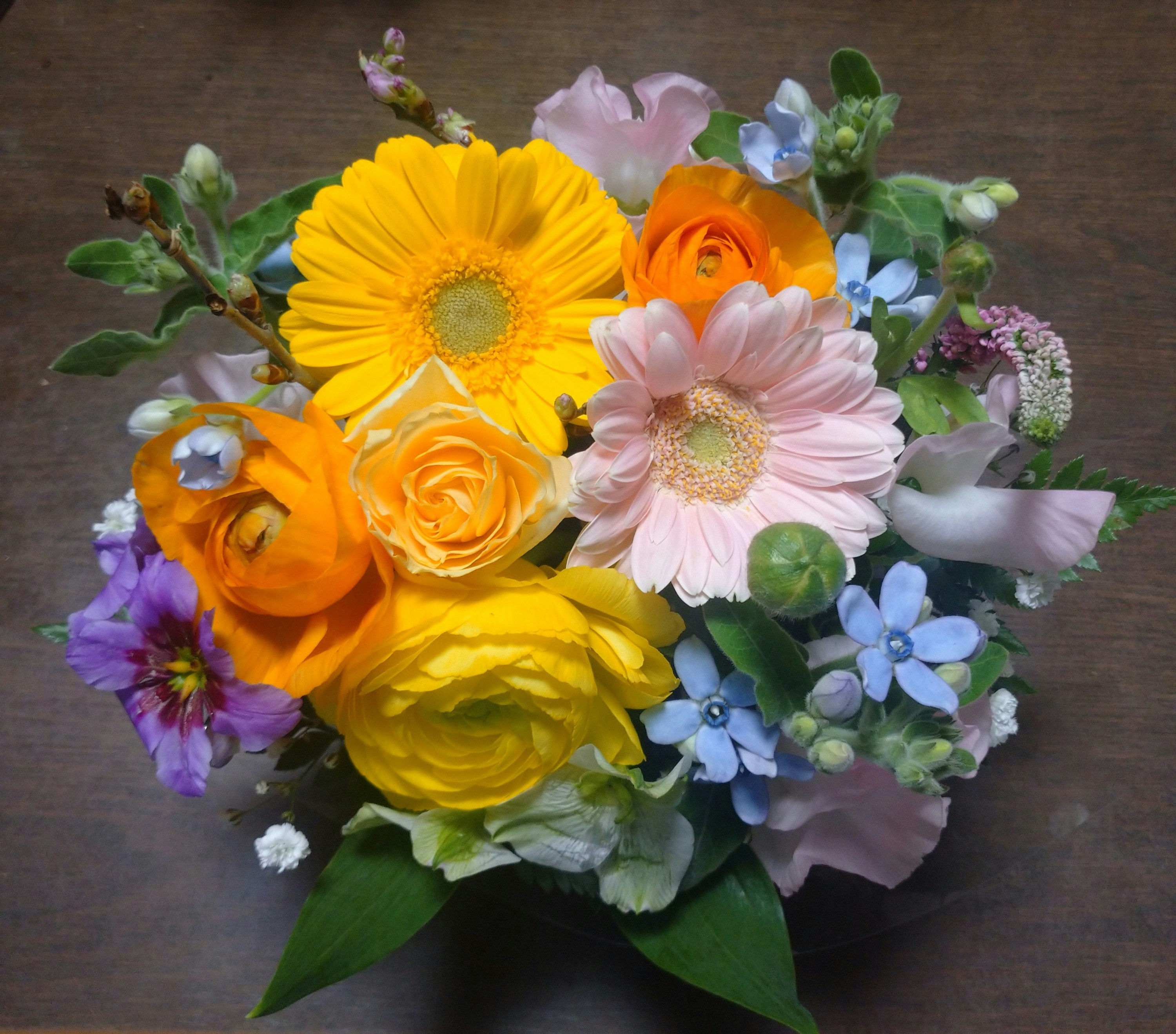arreglo floral de flores amarillas y rosas sobre fondo de madera