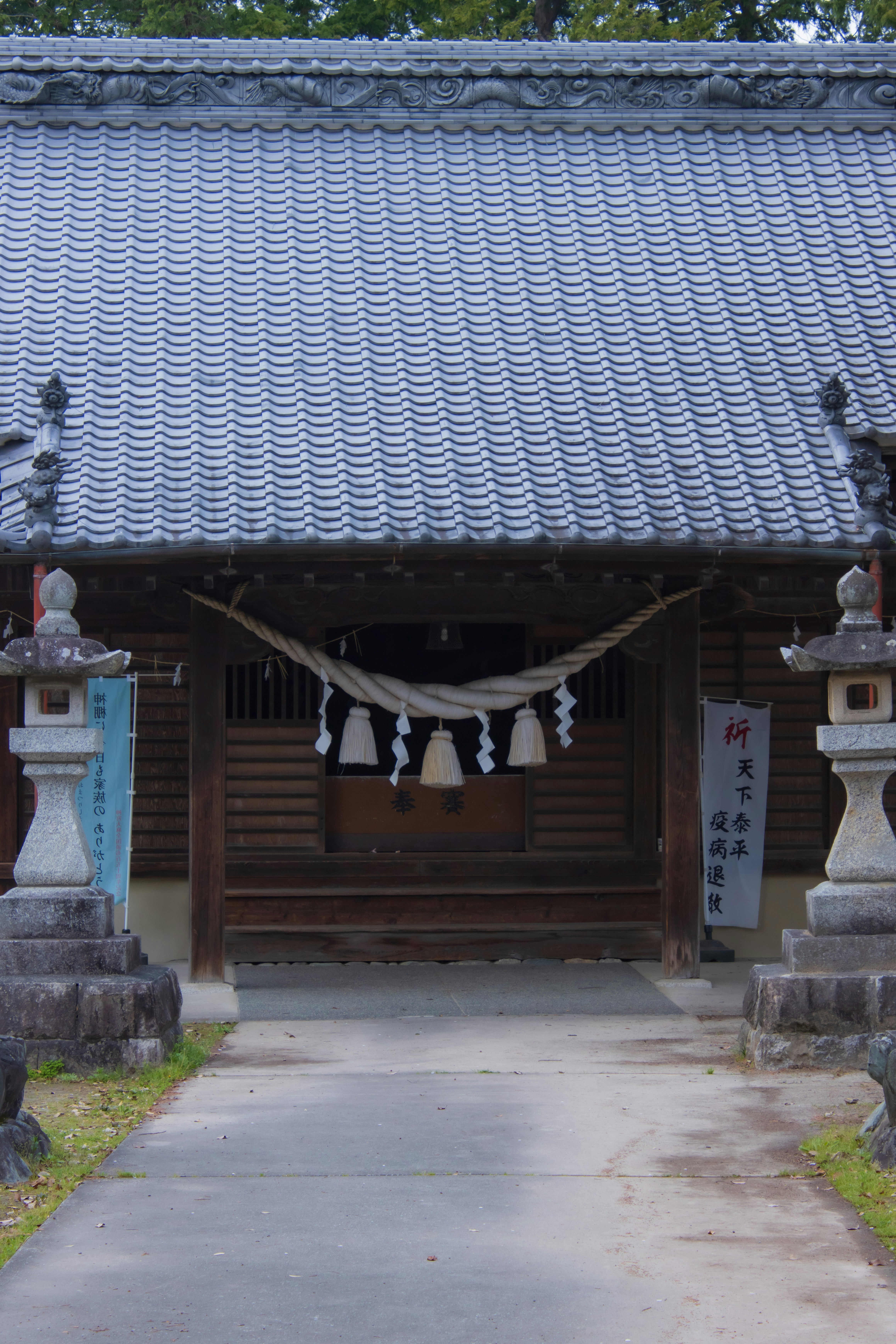 伝統的な日本の寺院の入り口、屋根は瓦で覆われており、装飾的な提灯が吊るされている