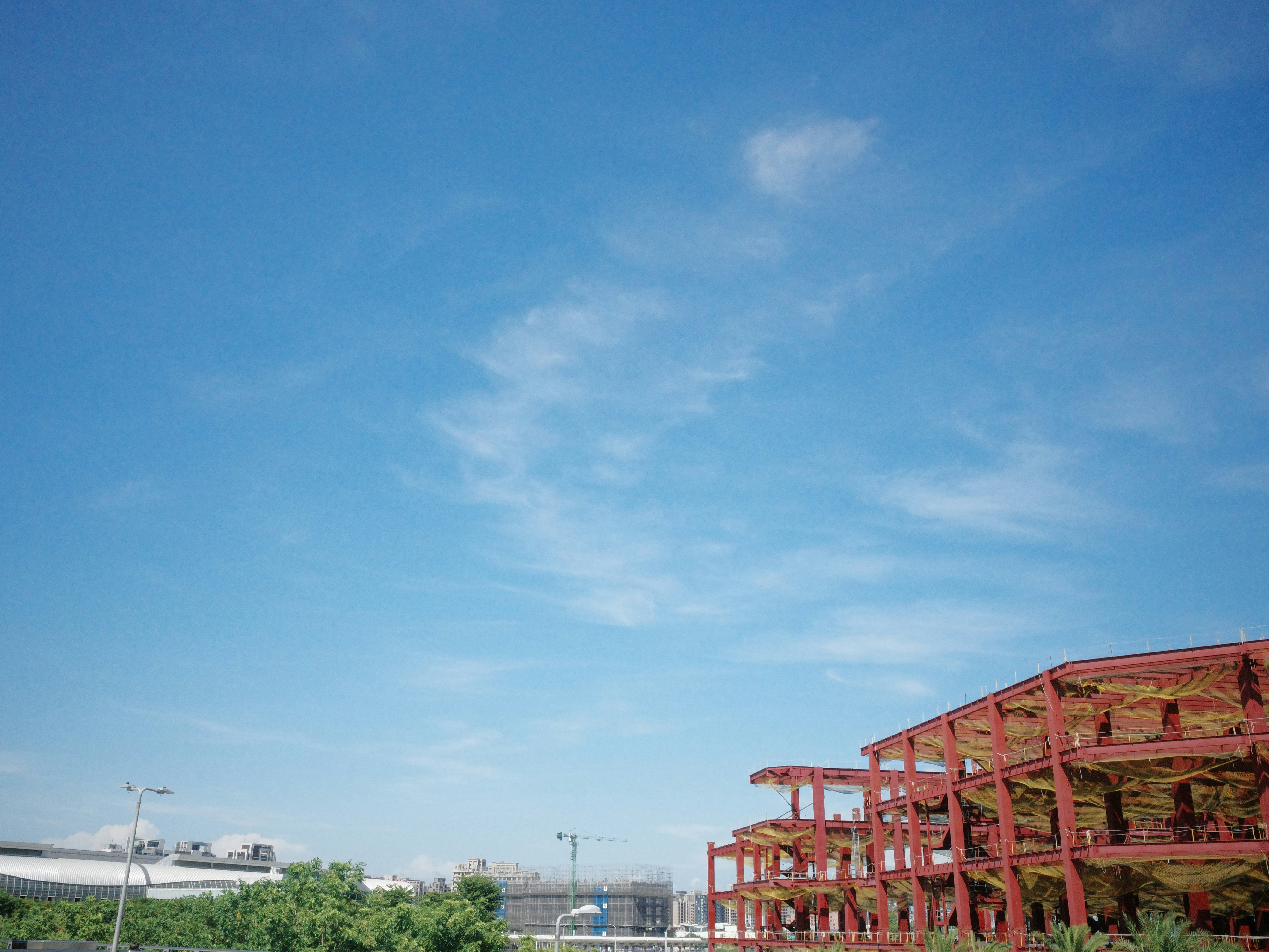 青空の下に広がる赤い鉄骨の構造物と港の景色