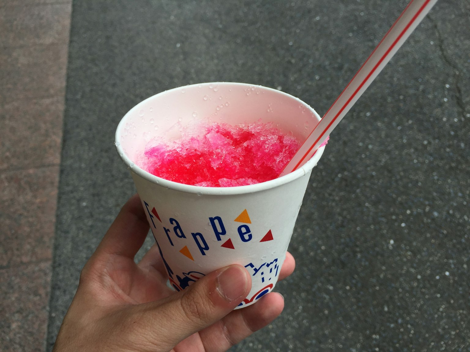 Mano sosteniendo un vaso de hielo raspado rojo