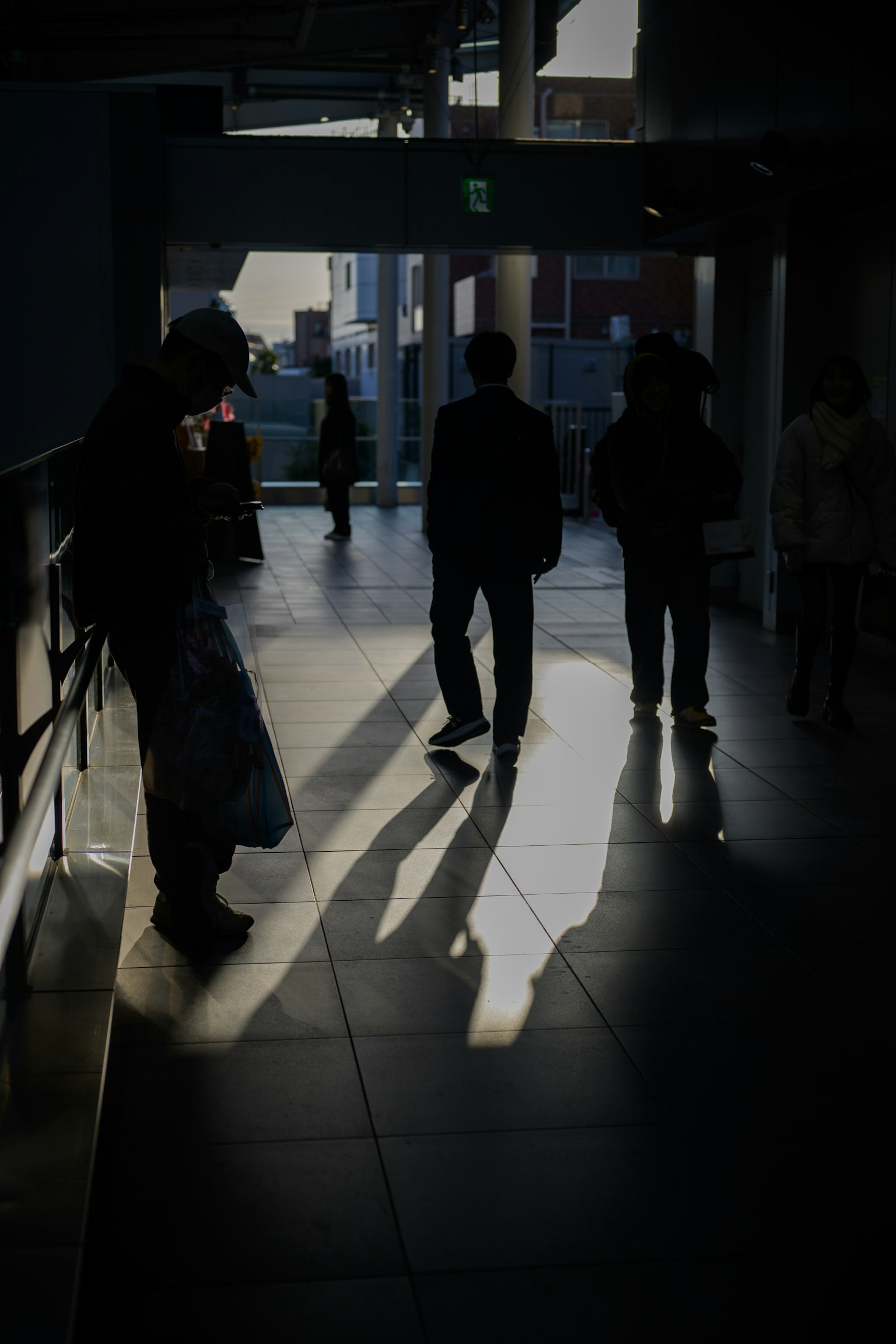 Silhouettes of people in a dimly lit station with long shadows