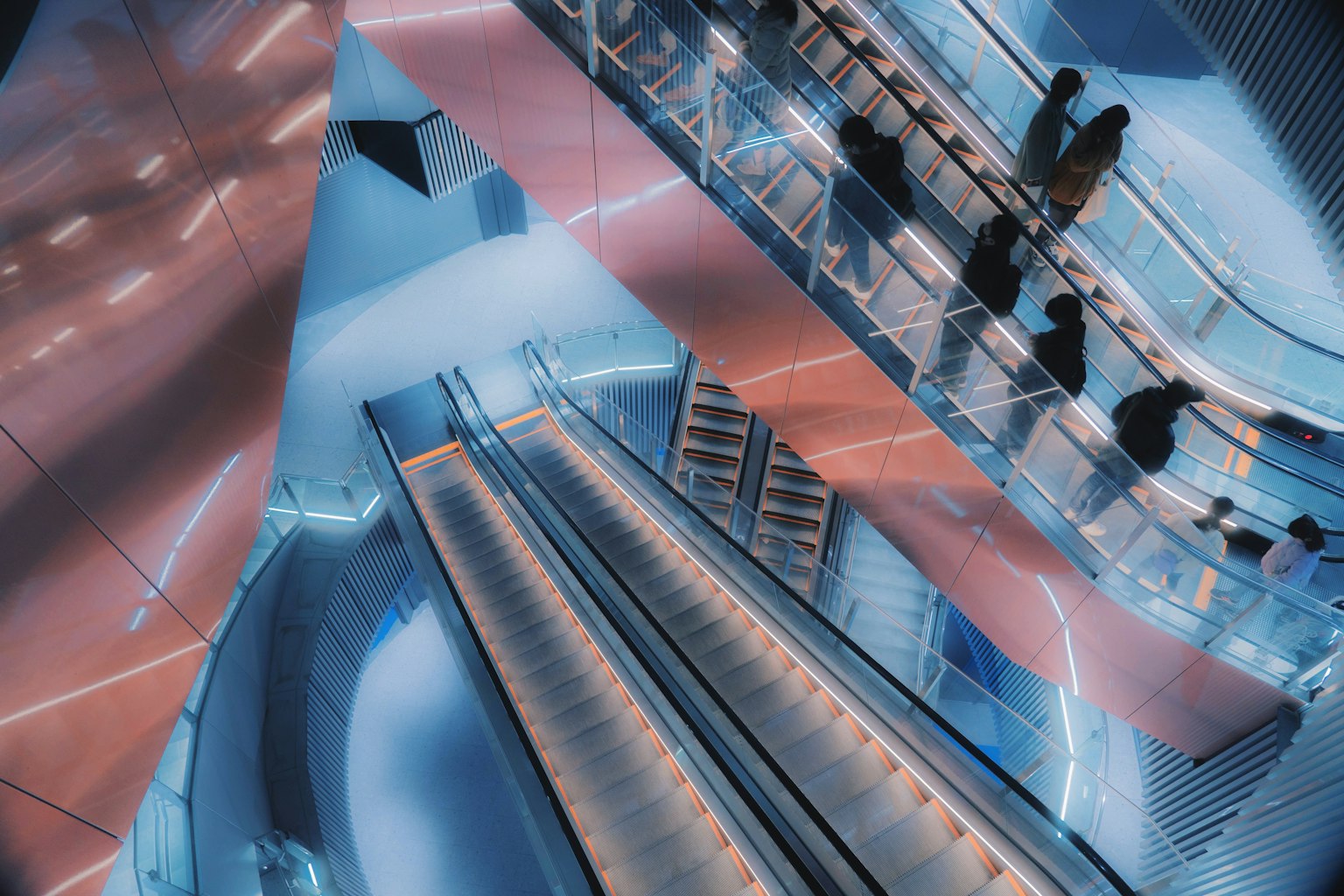 Futuristic interior with escalators and silhouettes of people