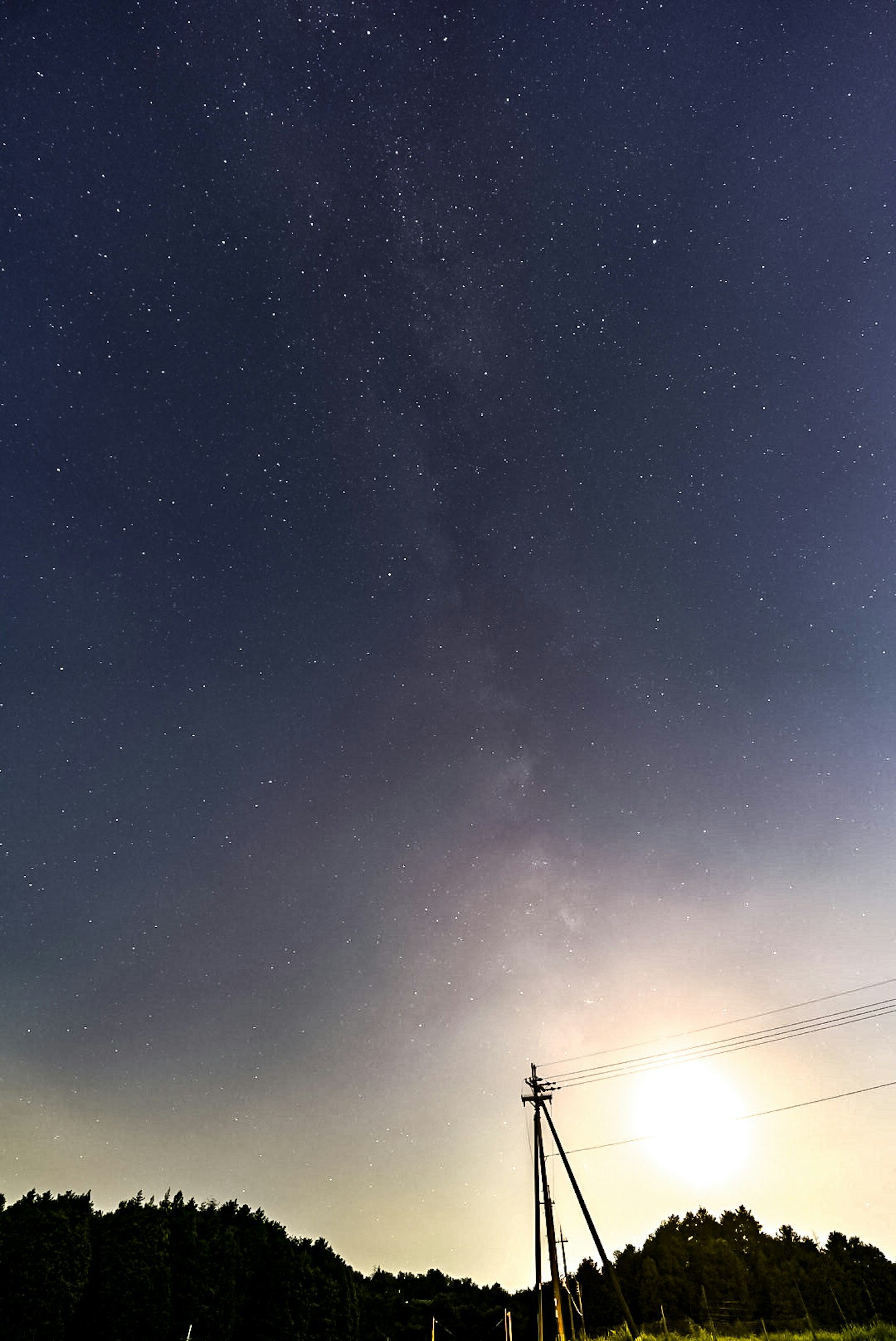 Cielo nocturno lleno de estrellas y un poste de electricidad