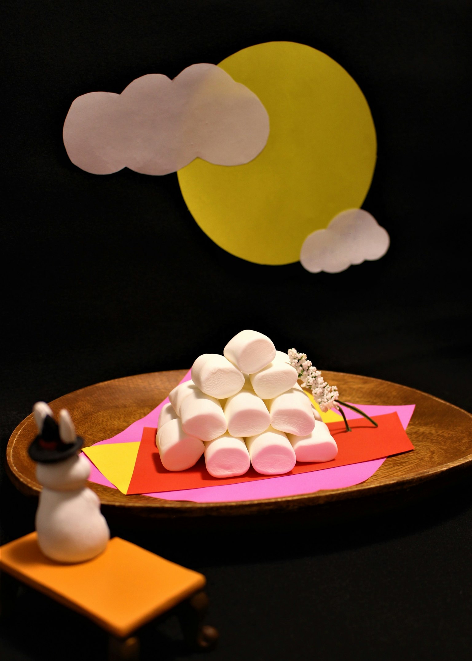 A snowman beside a colorful paper backdrop featuring a mountain of marshmallows