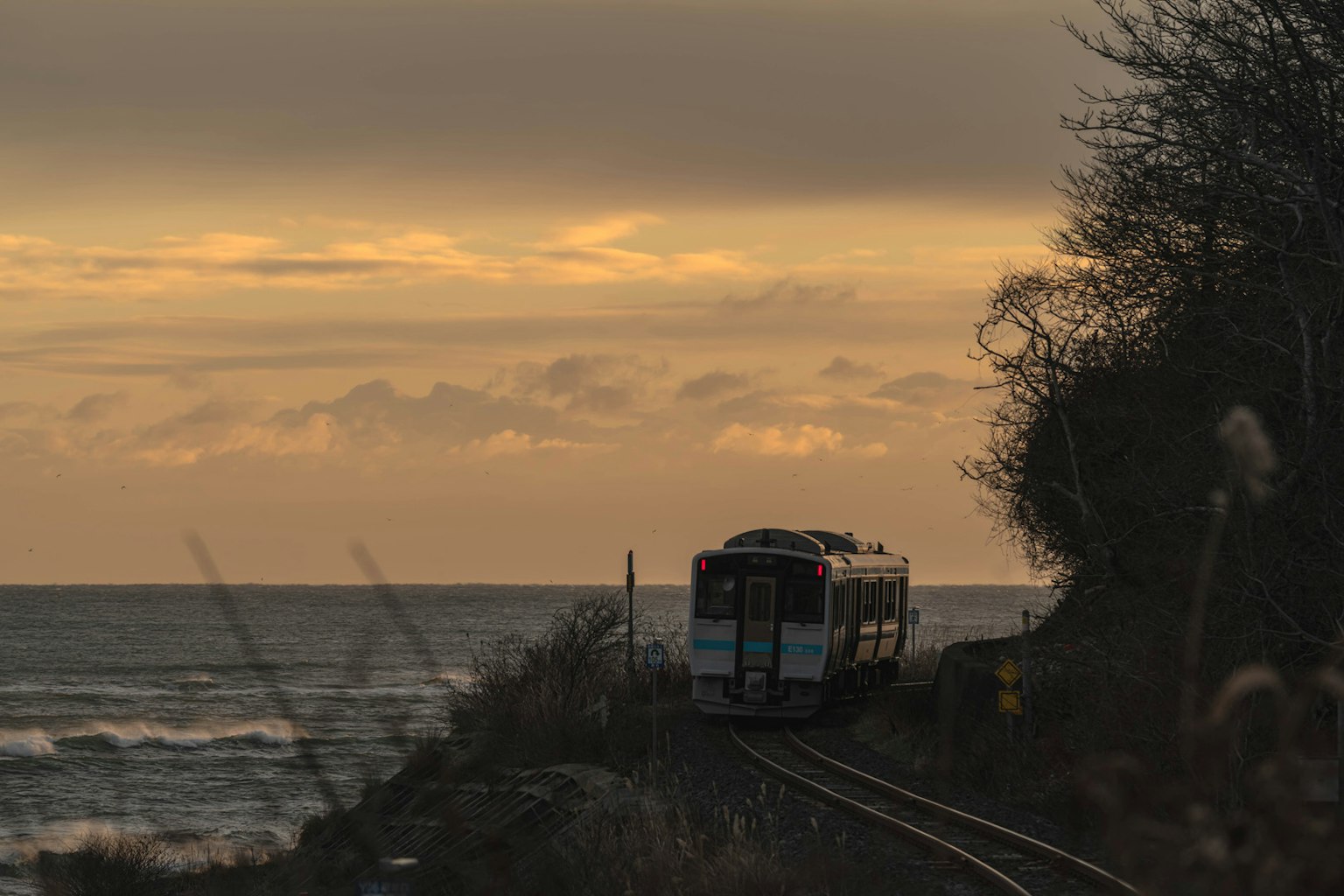 沿海行駛的火車在日落時分與軌道和海洋景觀