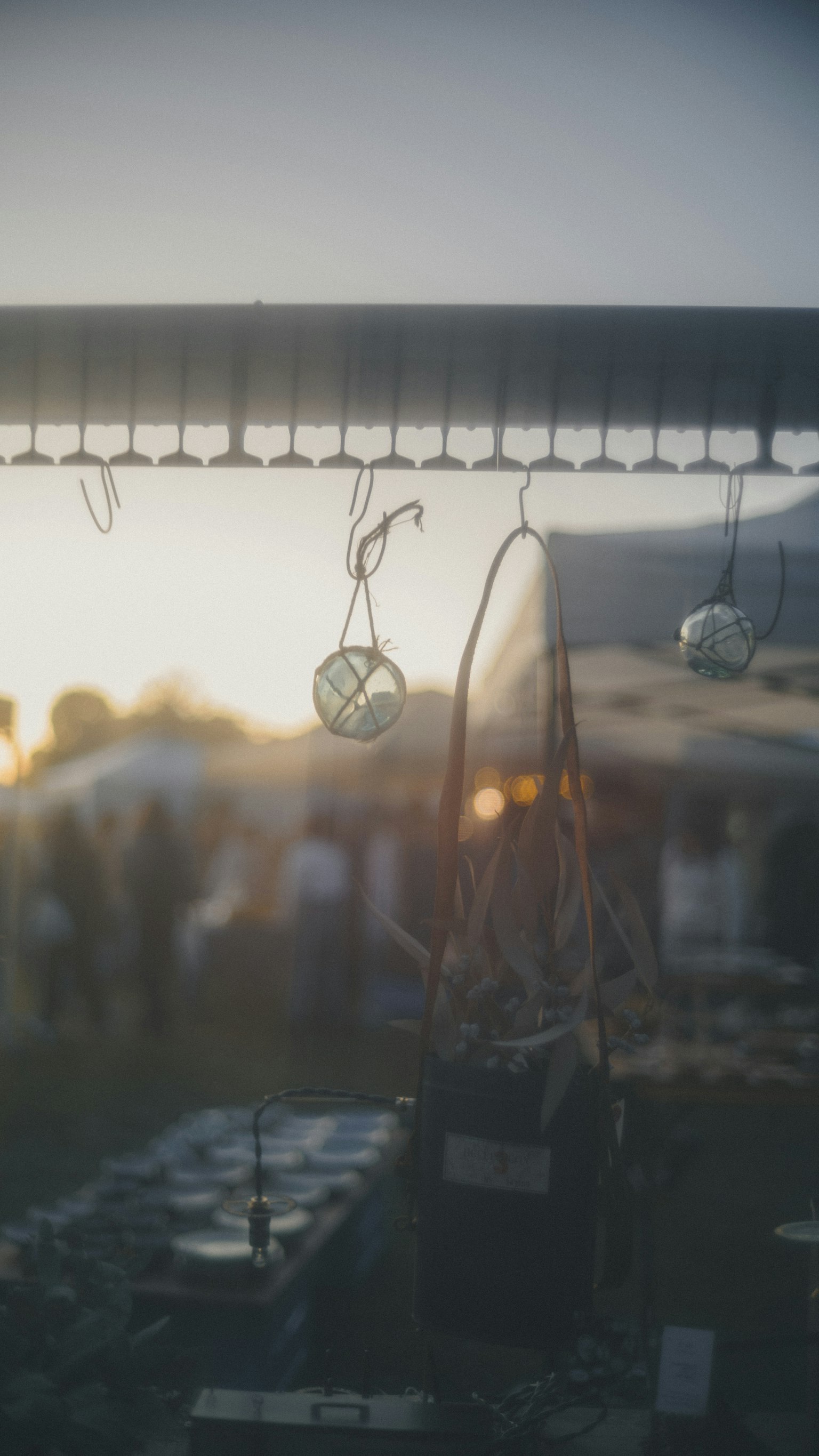 夕暮れ時のマーケットで吊るされた装飾品と背景の人々