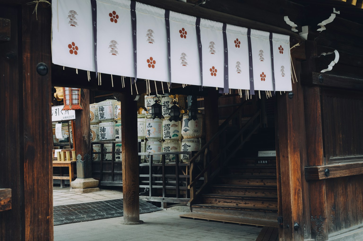 木制神社的入口，悬挂着白色帷幕和清酒桶