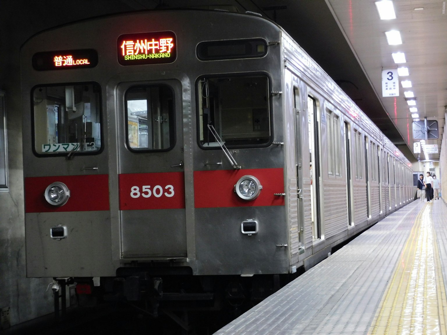 Silver train with red stripe stopped at the station