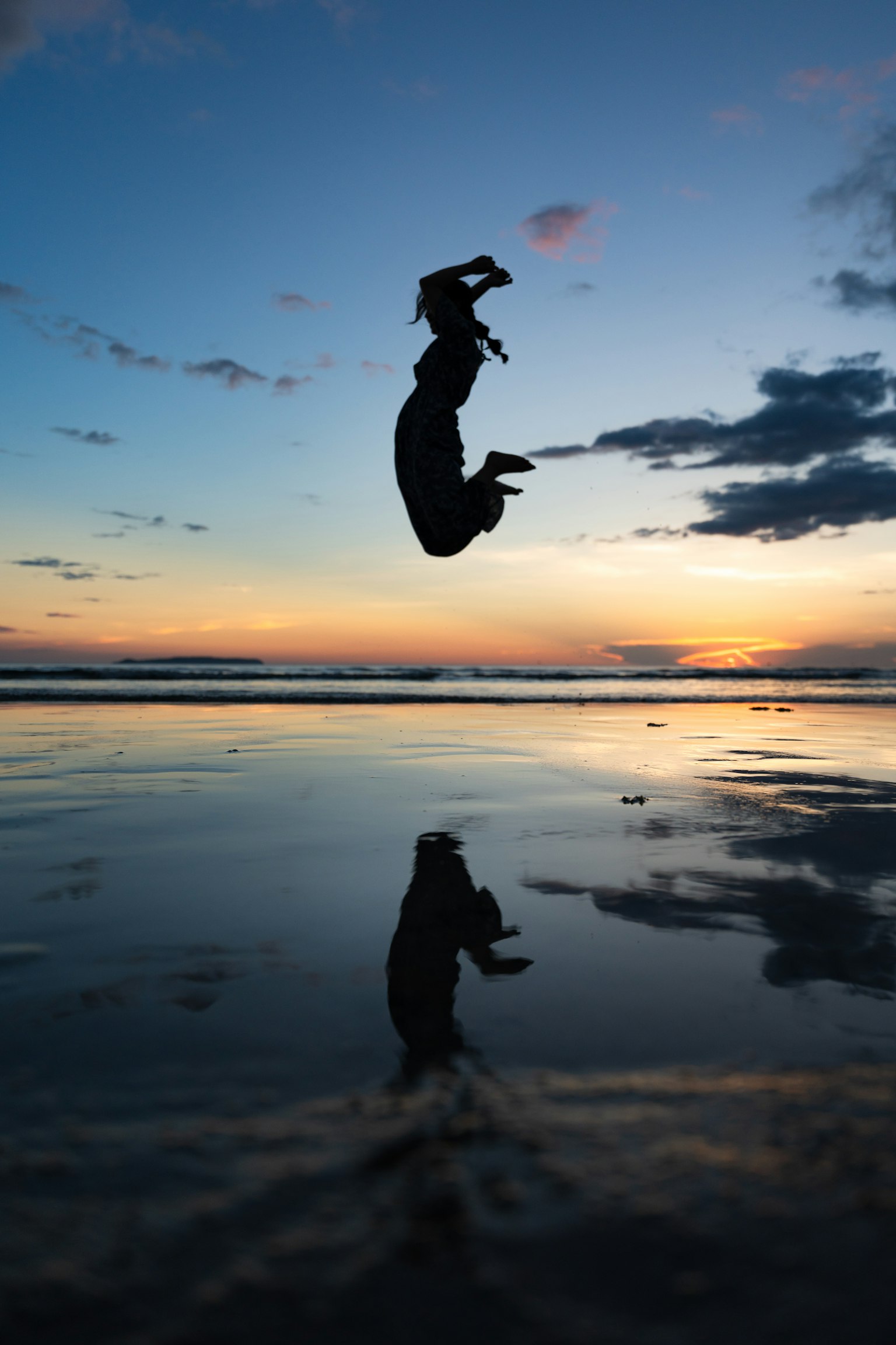 Silhouette einer Person, die im Meer bei Sonnenuntergang springt