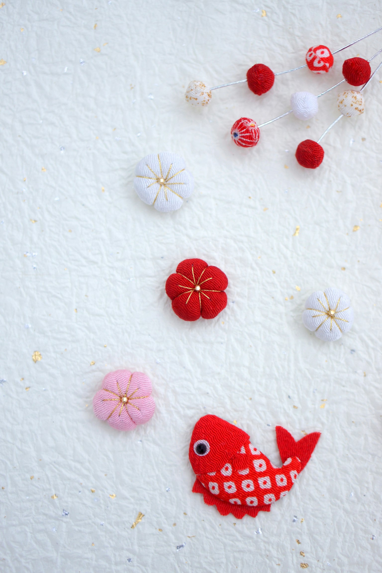 Colorful flowers and a red fish decoration arranged on a white background