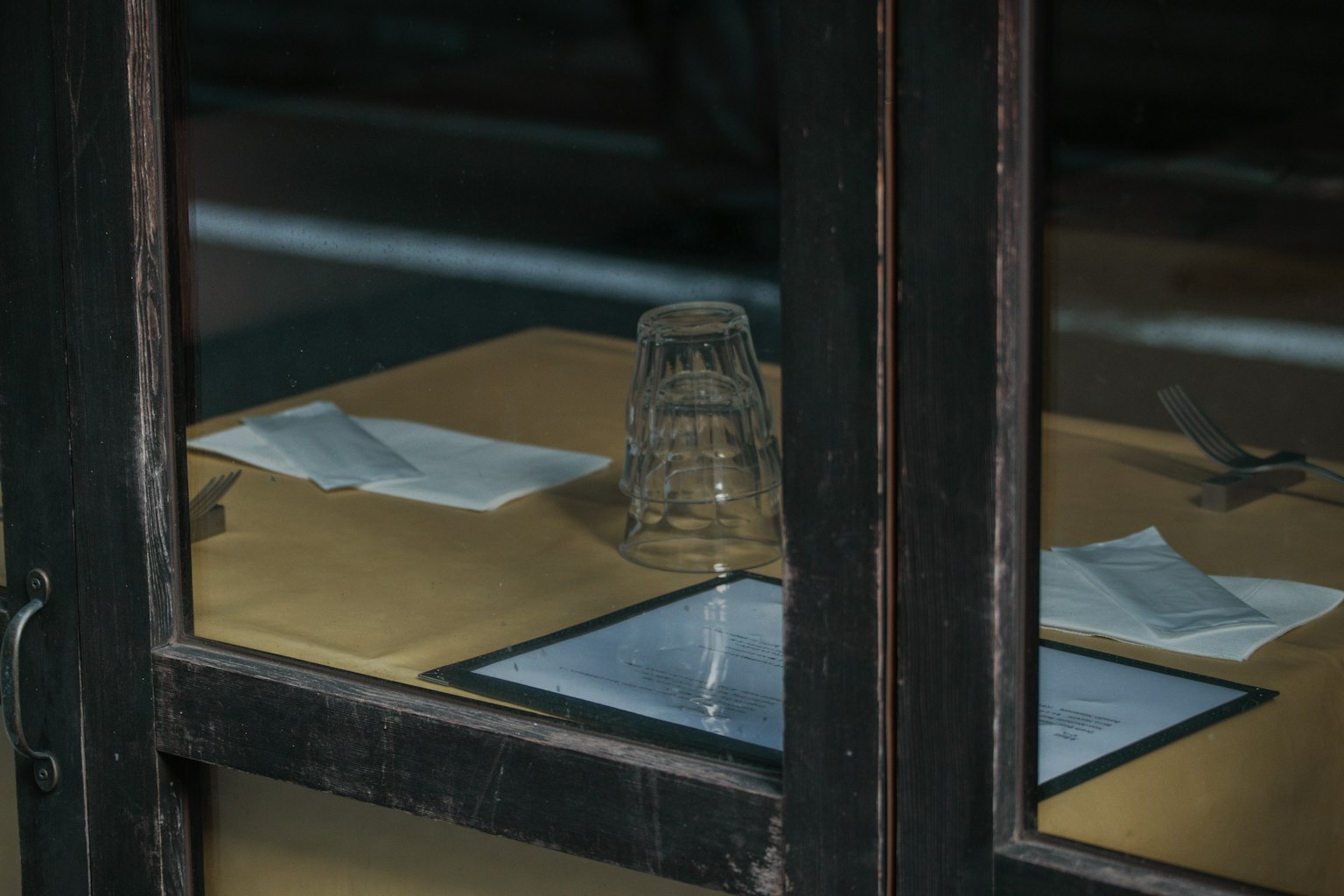 Blick durch das Fenster auf einen Tisch mit einem Glas und einer Speisekarte