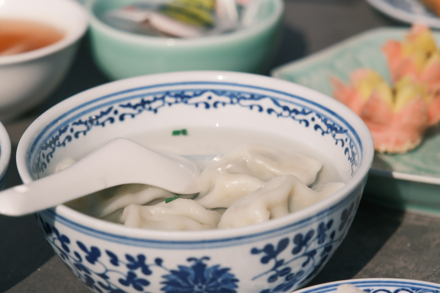 Bol avec des raviolis dans une soupe blanche avec des motifs floraux bleus