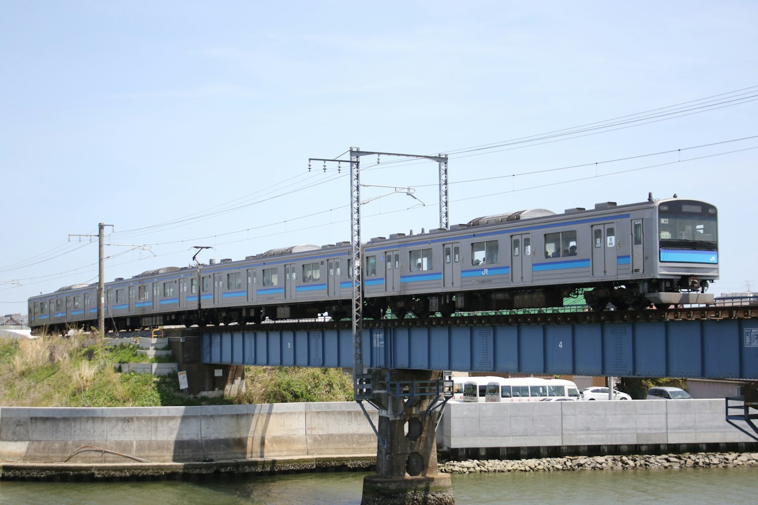 Blue train running over a bridge above the river