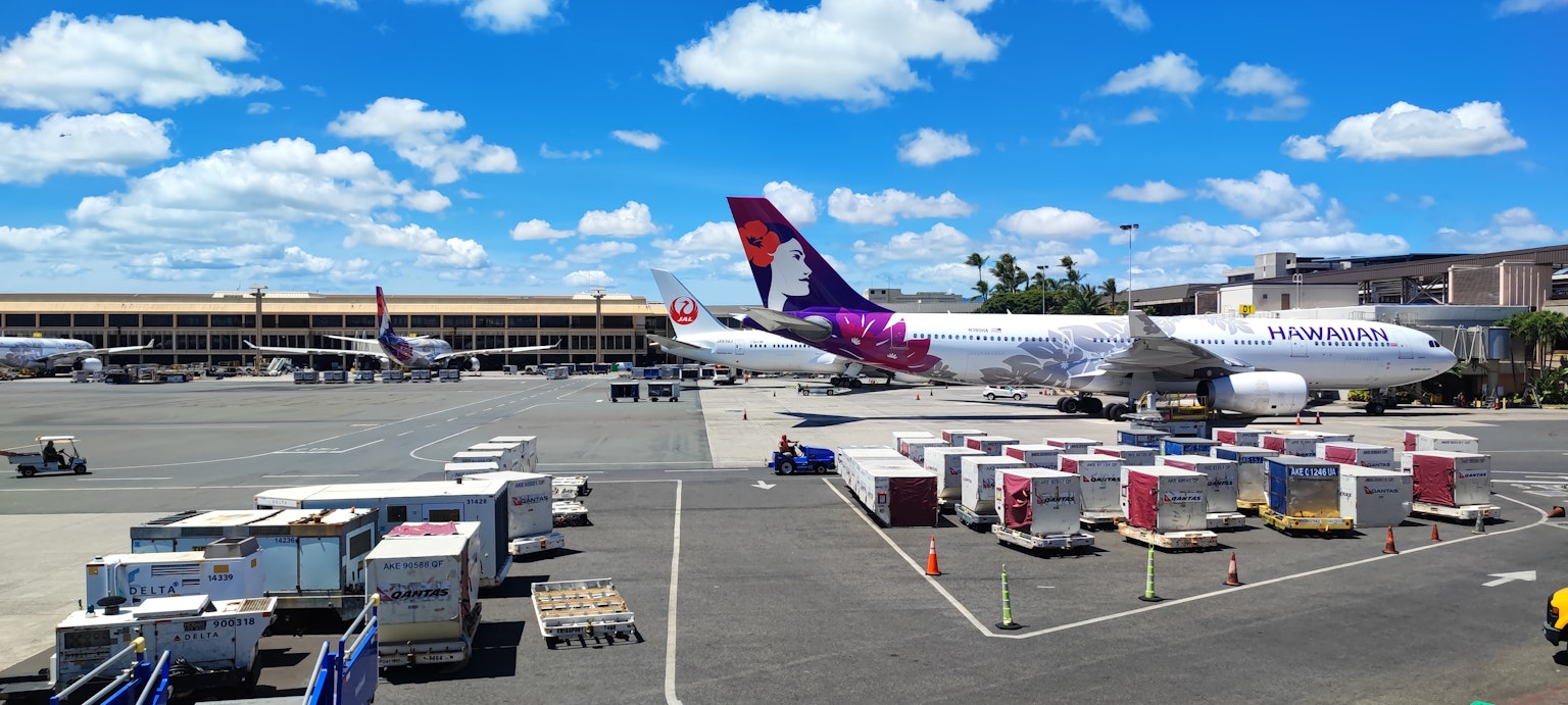 Avion d'Hawaiian Airlines stationné sur la piste d'aéroport sous un ciel bleu
