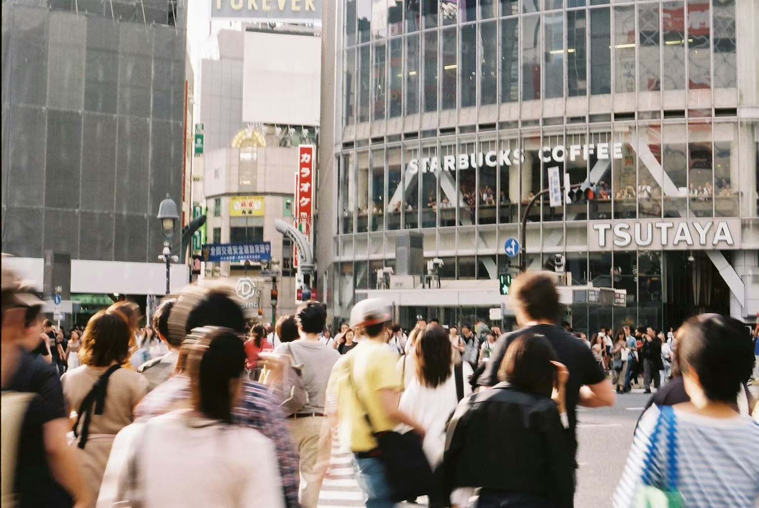 人群穿越澀谷十字路口，附近有星巴克咖啡和TSUTAYA