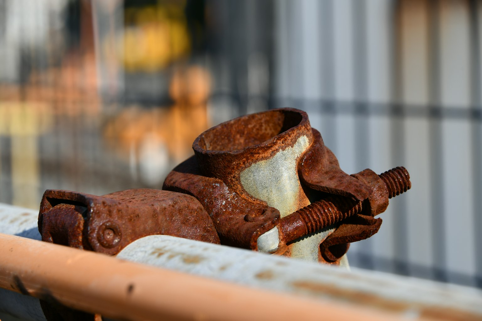 Rostiger Metallteil mit einer Schraube vor industriellem Hintergrund