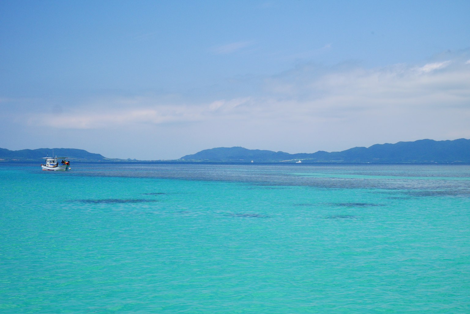 ทิวทัศน์ทะเลสีฟ้าและท้องฟ้าพร้อมเรืออยู่ในระยะไกล