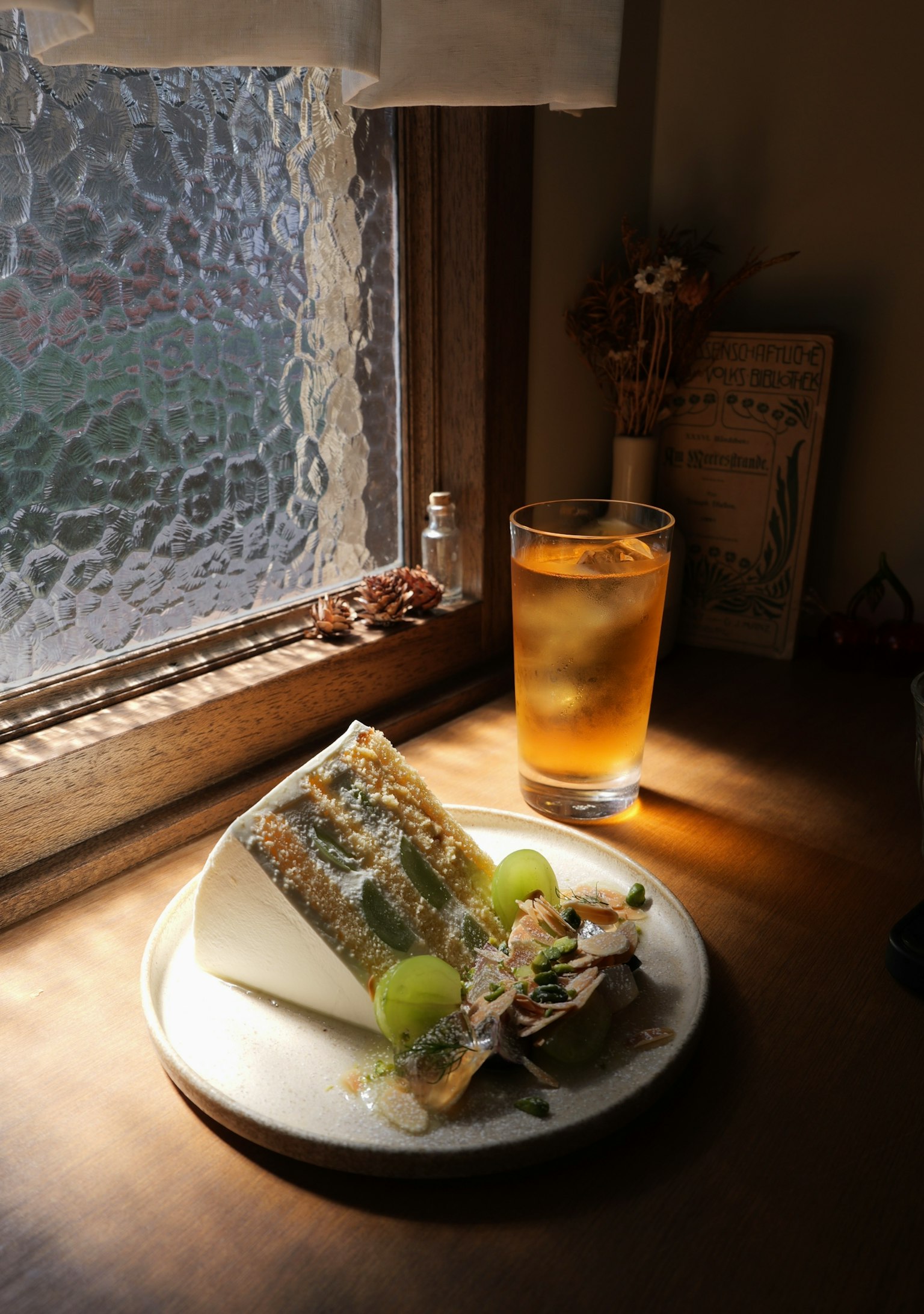 窓辺に置かれた美しいデザートとアイスティーの写真