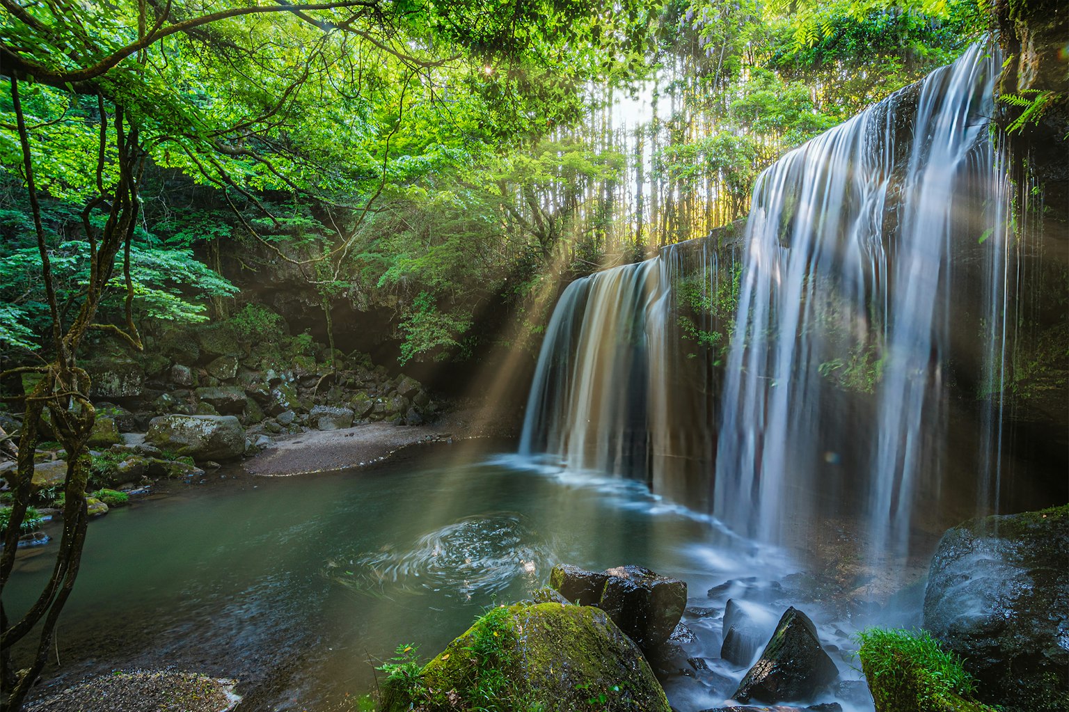 Air terjun indah dikelilingi oleh pepohonan rimbun Cahaya memantul di atas air yang mengalir