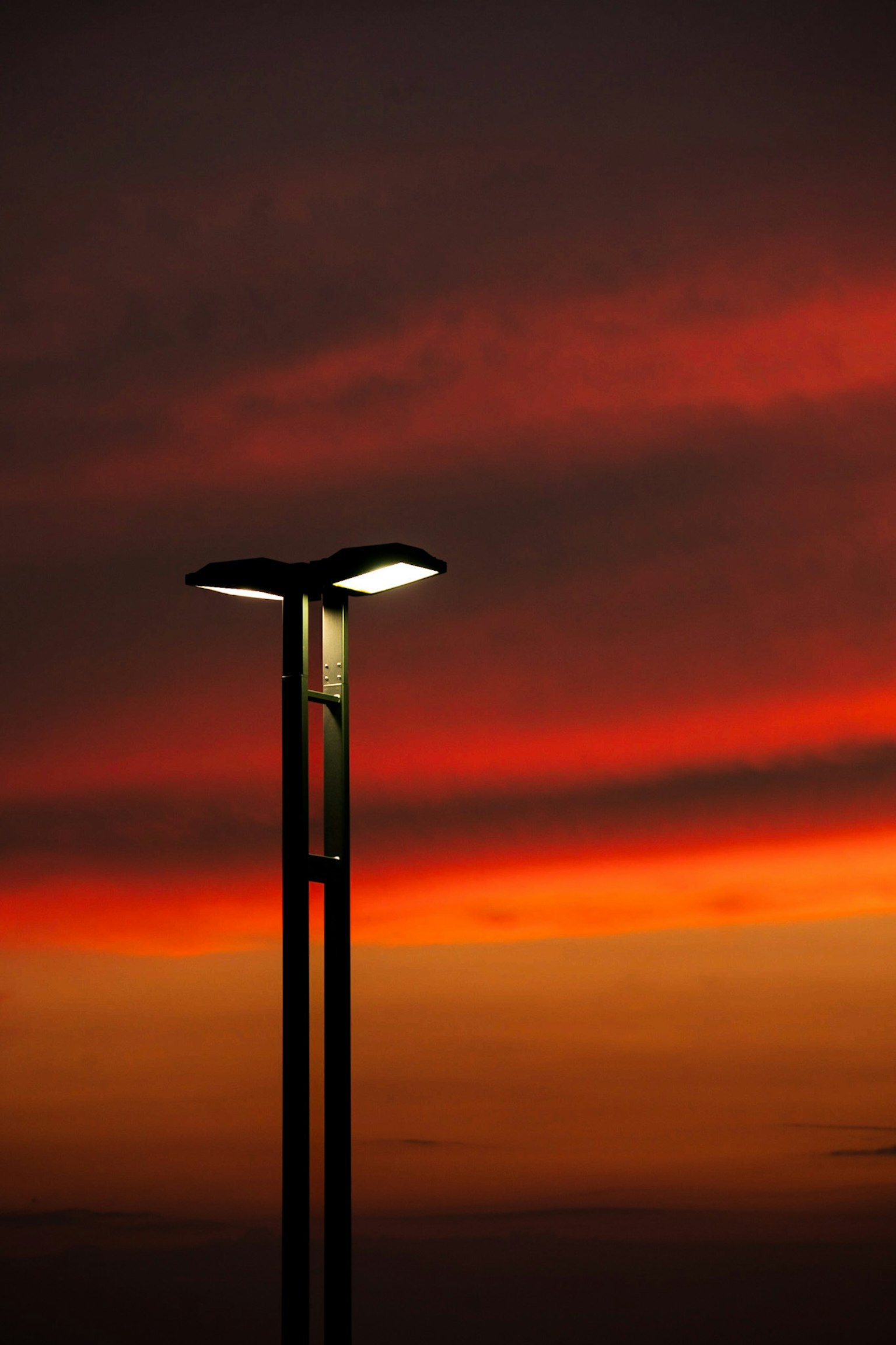 Silhouette einer Straßenlampe, beleuchtet von der Abenddämmerung