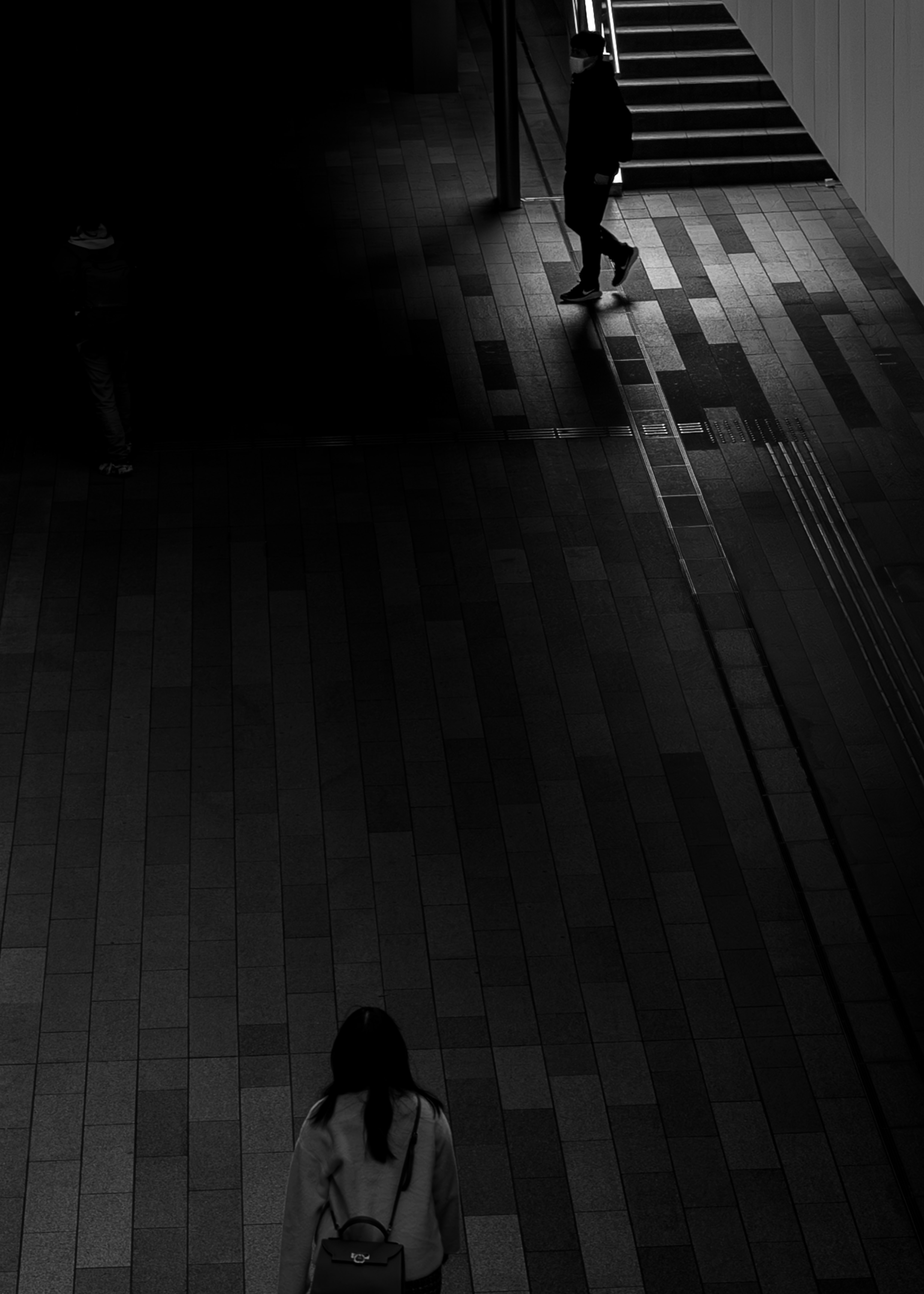 暗い空間で歩く二人の人物と木の床