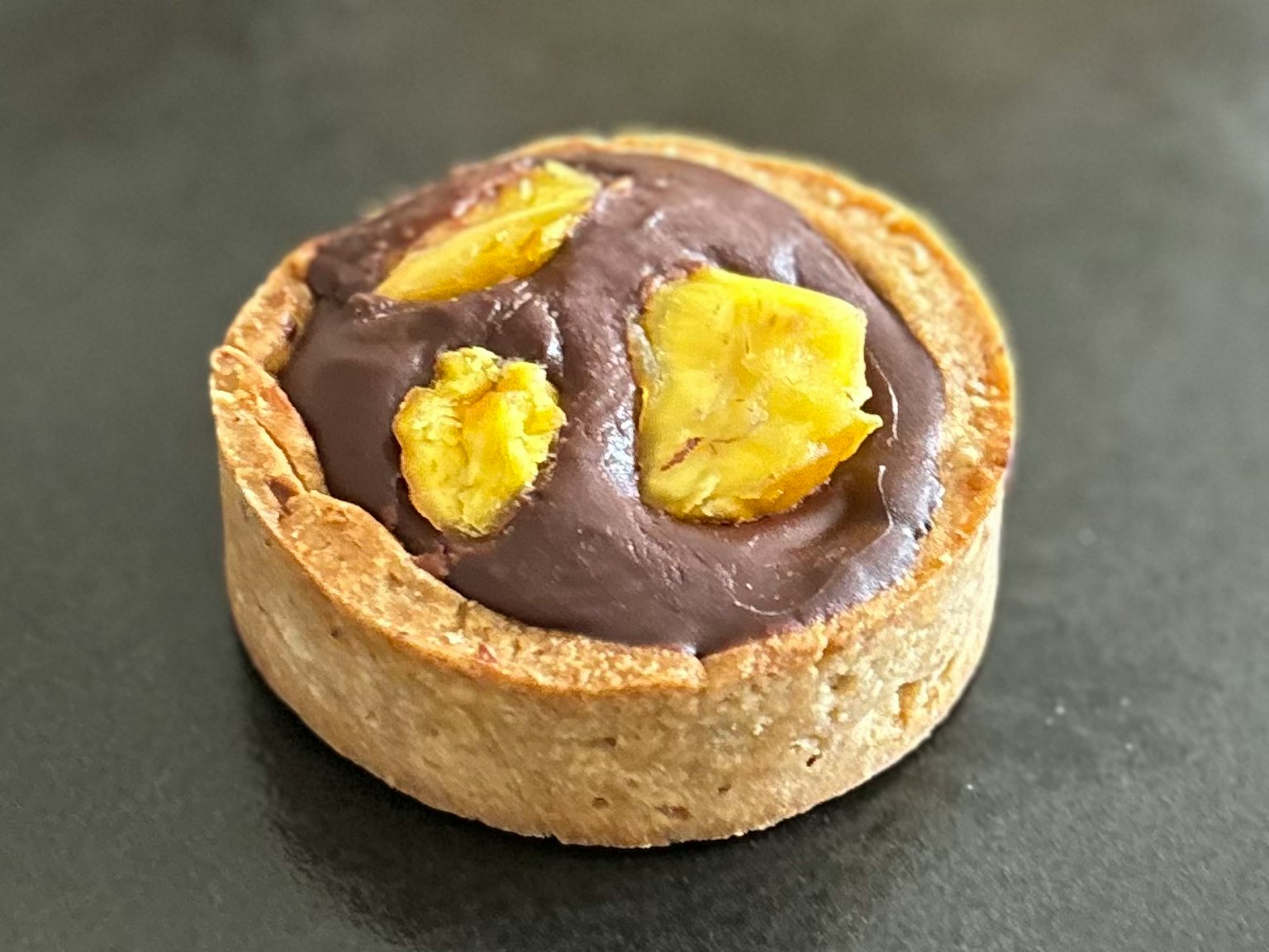 Chocolate and banana tart featuring a crust topped with chocolate cream and banana slices