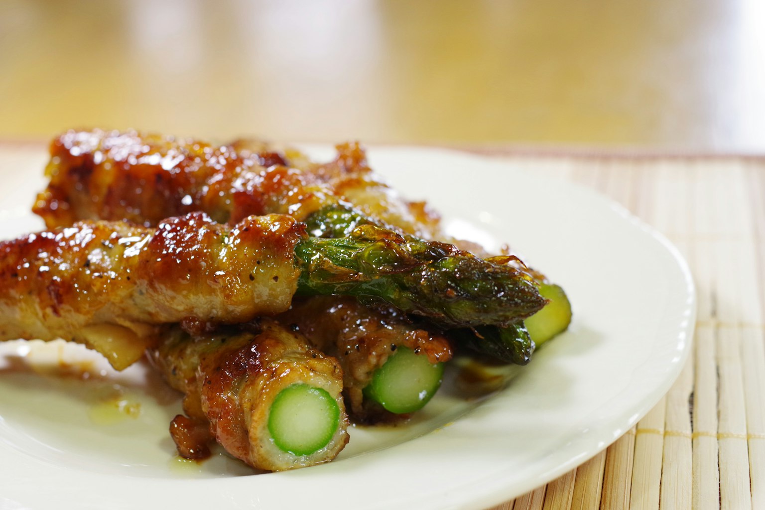 광택이 나는 유약을 입힌 고기 감싼 아스파라거스 접시