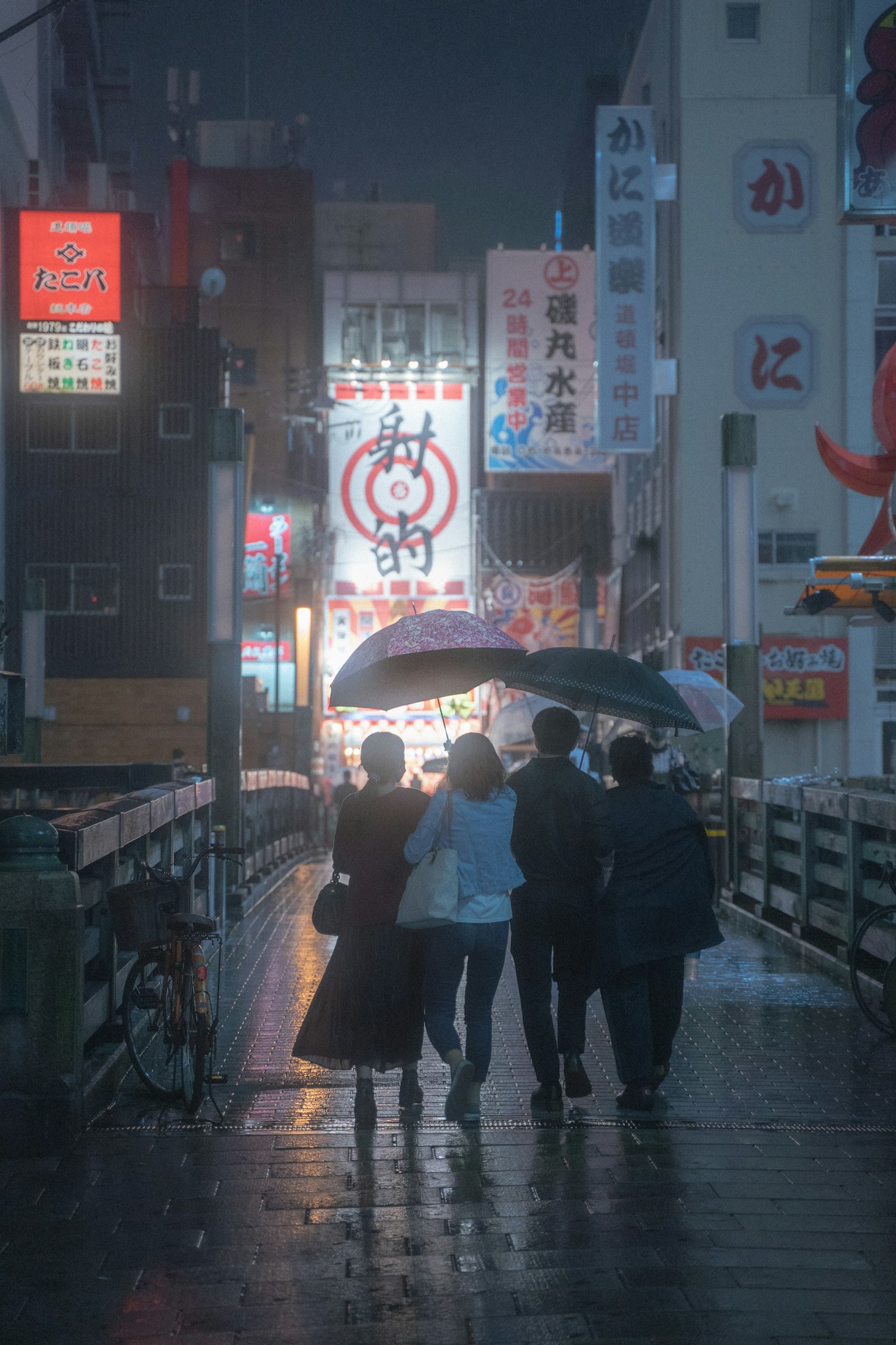 Silhouette di persone che camminano sotto ombrelli nella pioggia con insegne al neon vivaci in una città animata