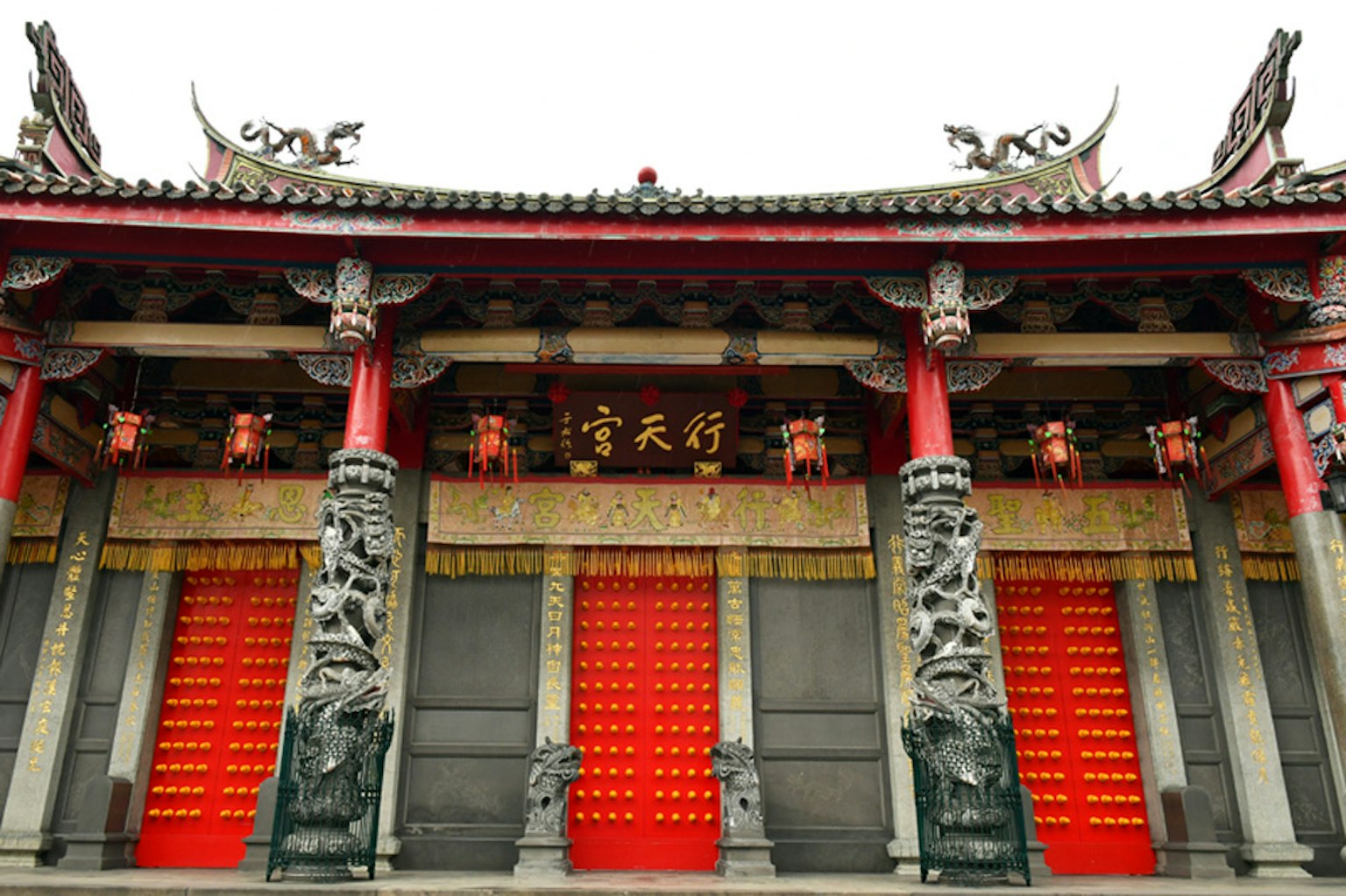 Facciata di un tempio cinese tradizionale con porte rosse e intagli intricati