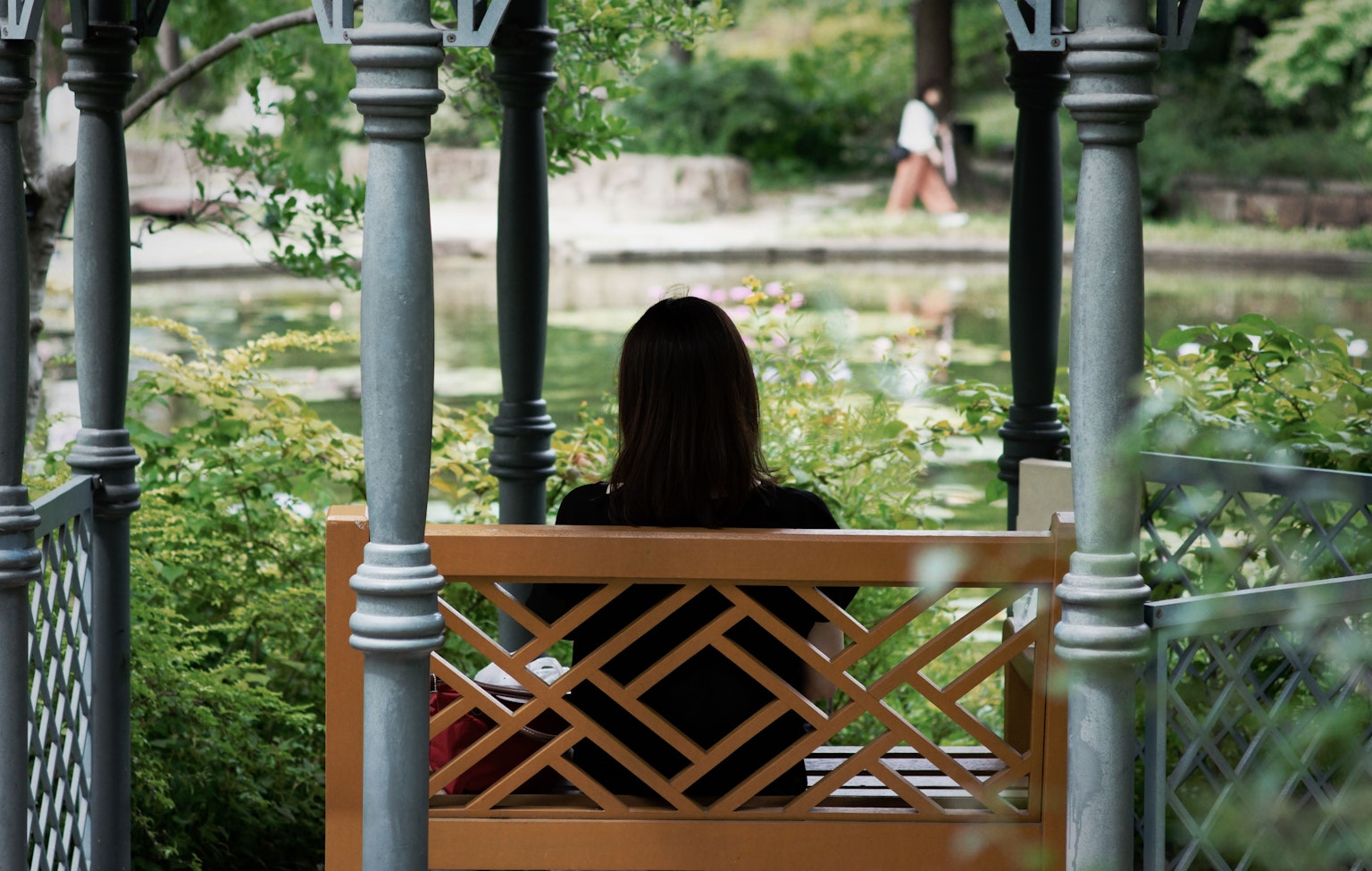Femme assise sur un banc surplombant un étang dans un parc