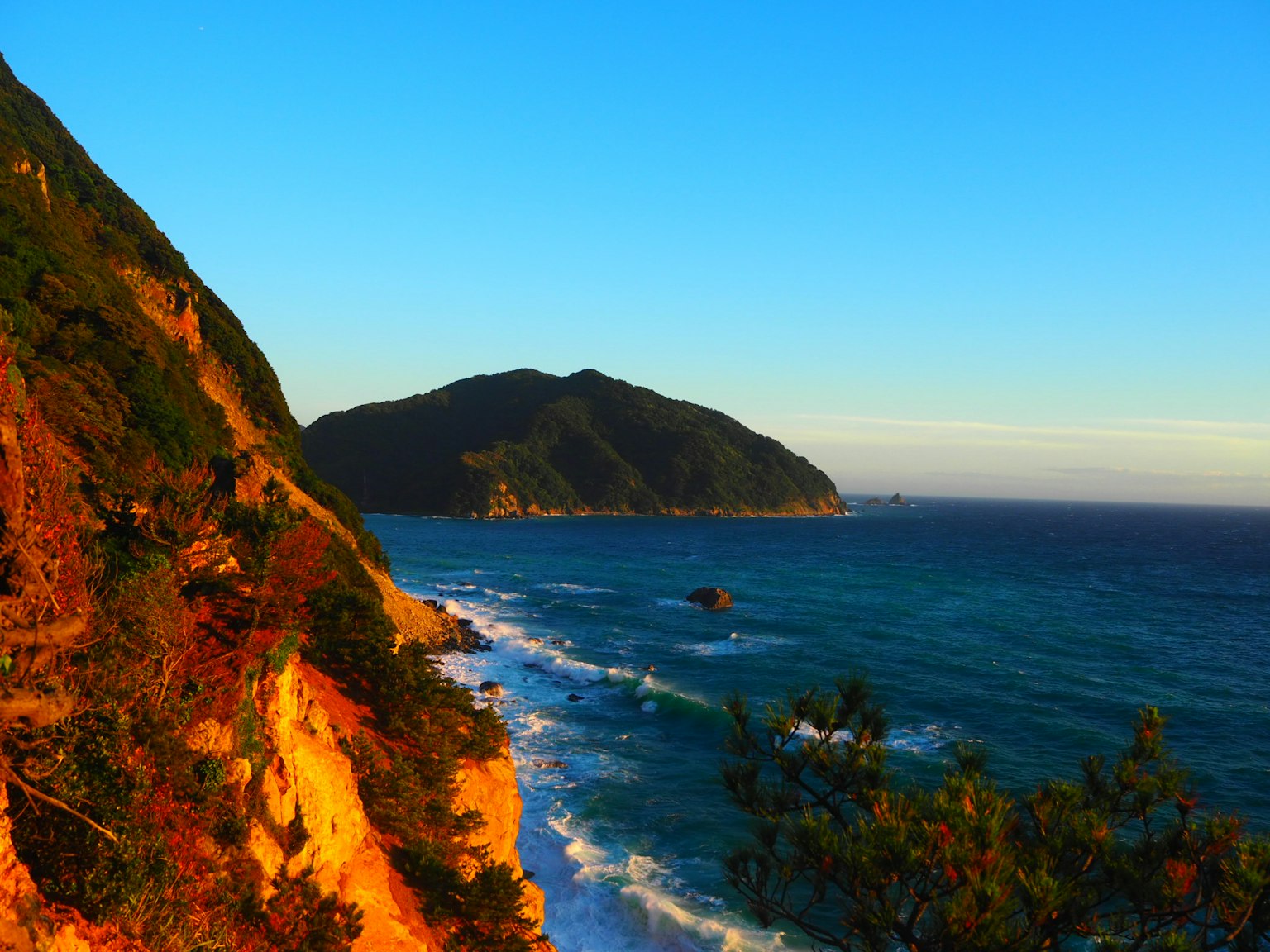 Pemandangan pantai dengan langit biru gunung dan gelombang dalam pemandangan yang indah