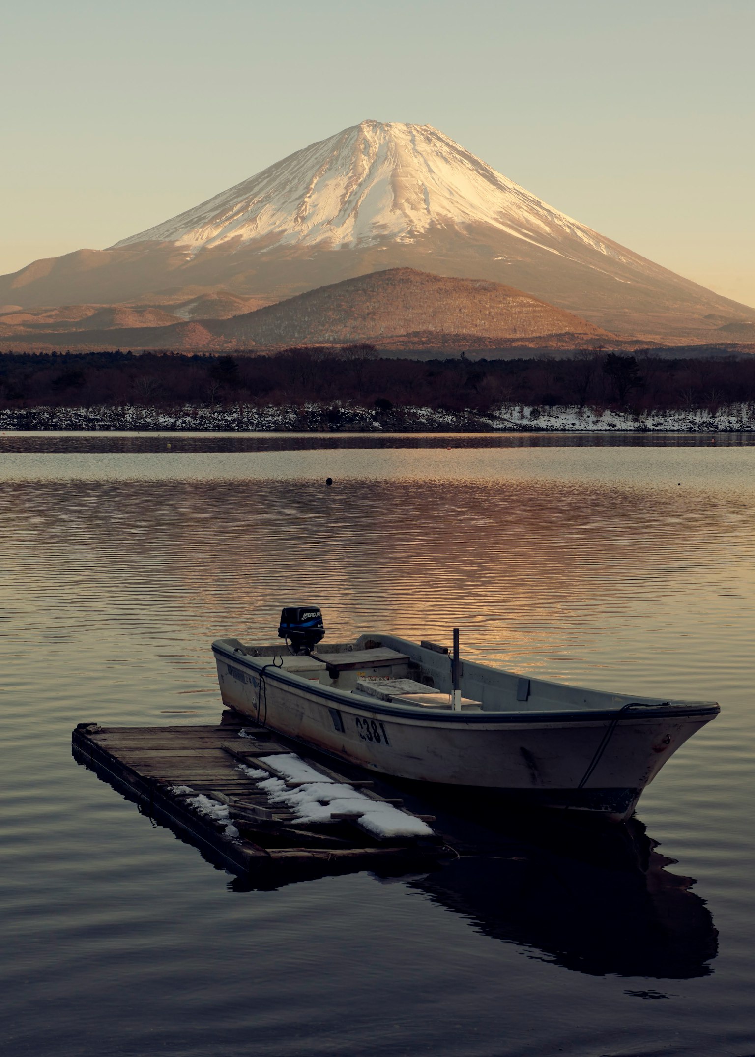 Un petit bateau flottant sur un lac calme avec le mont Fuji en arrière-plan