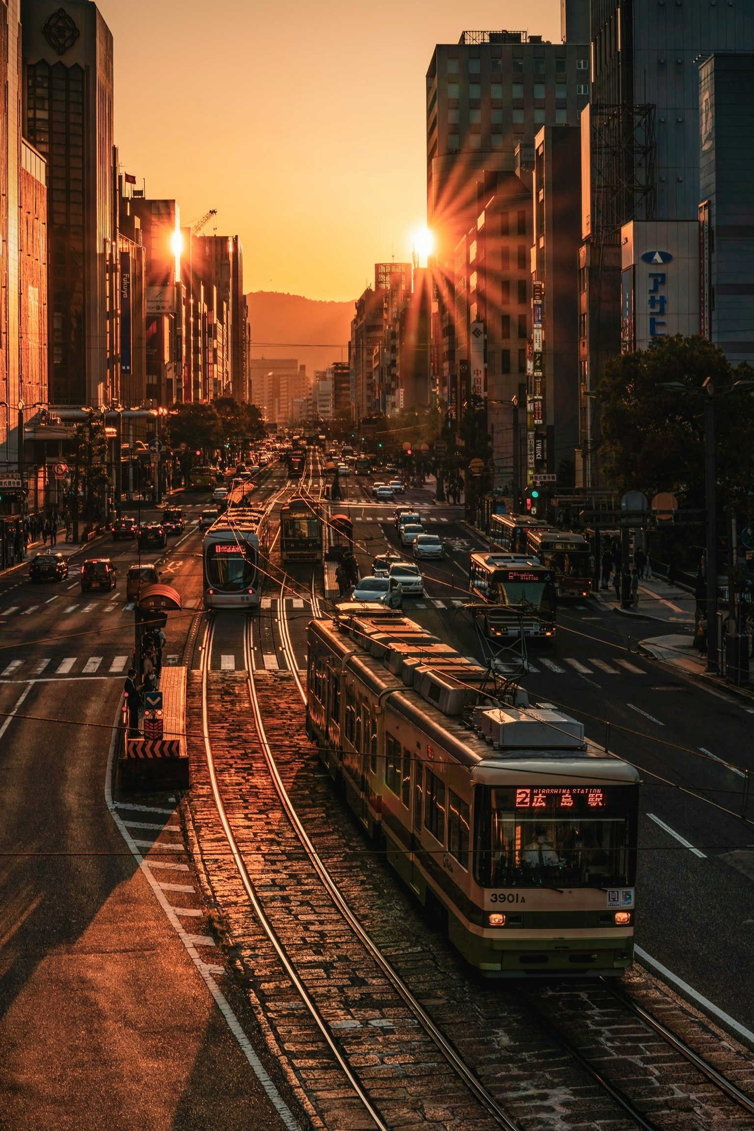 Tram running on city street with sunset and skyscrapers
