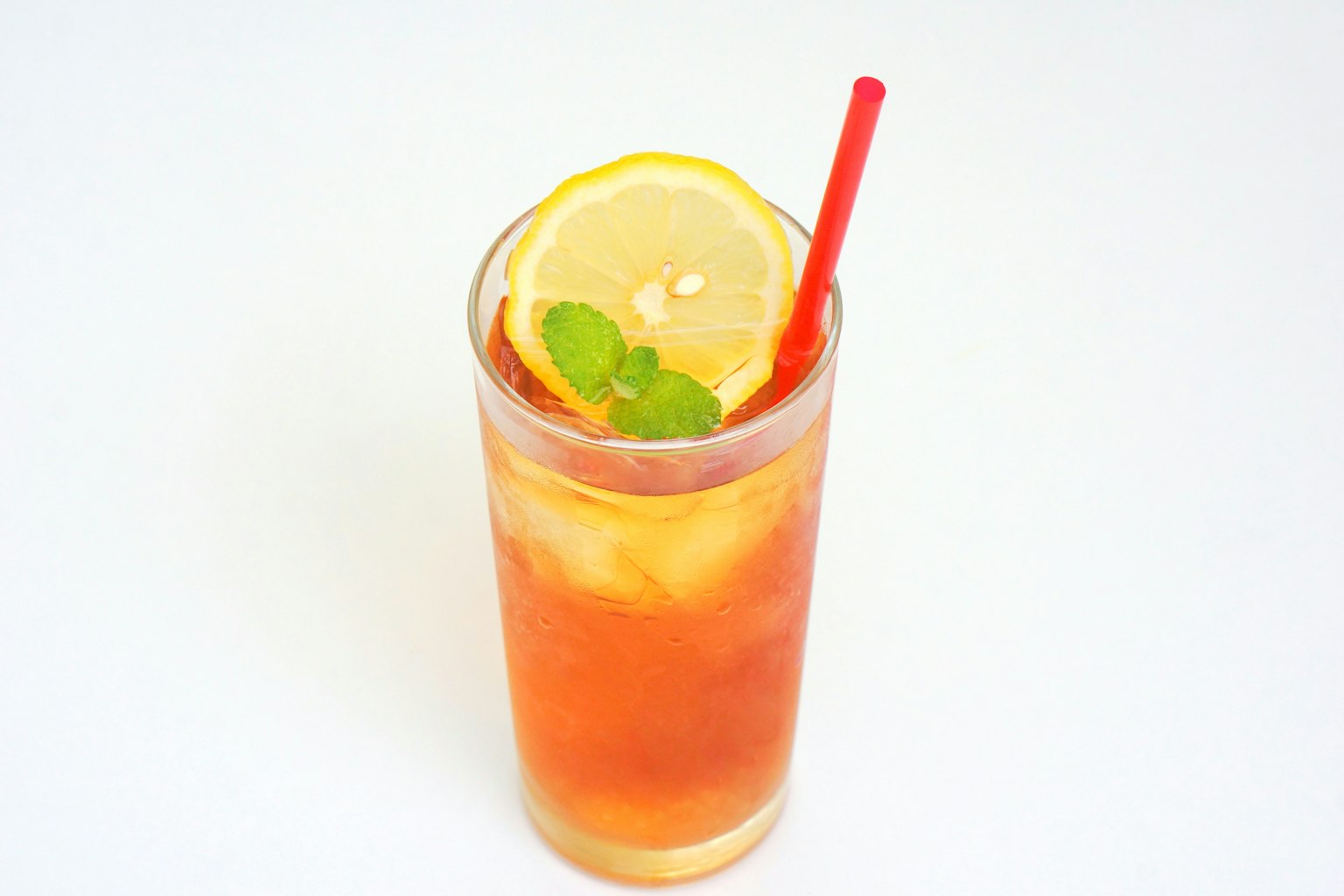 Un bicchiere di tè freddo con fette di limone e foglie di menta