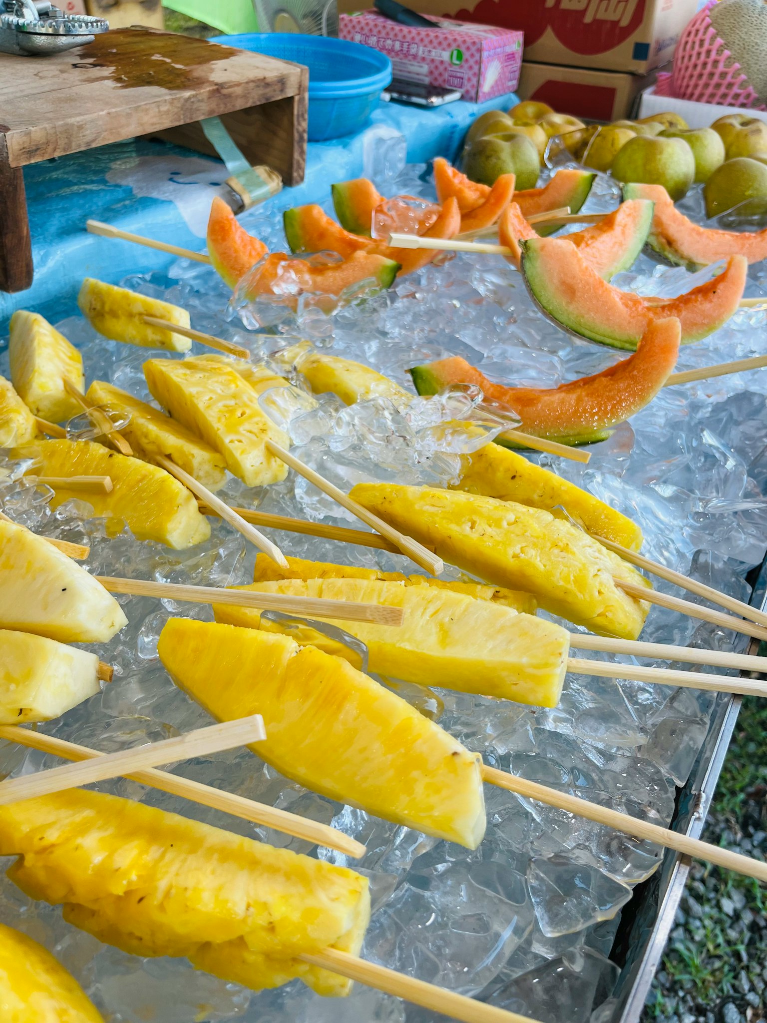 Spiedini di frutta disposti su ghiaccio con ananas e melone