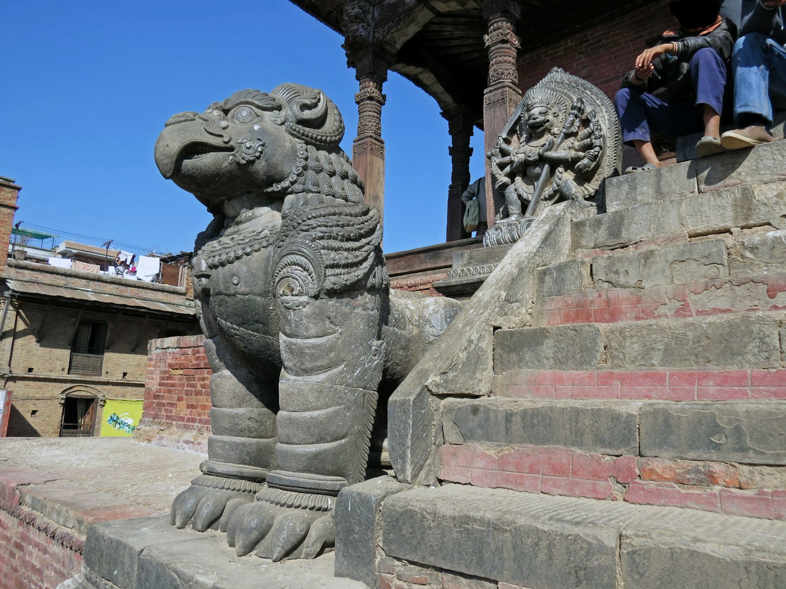 Sculpture de lion en pierre assise sur des marches sous un ciel bleu