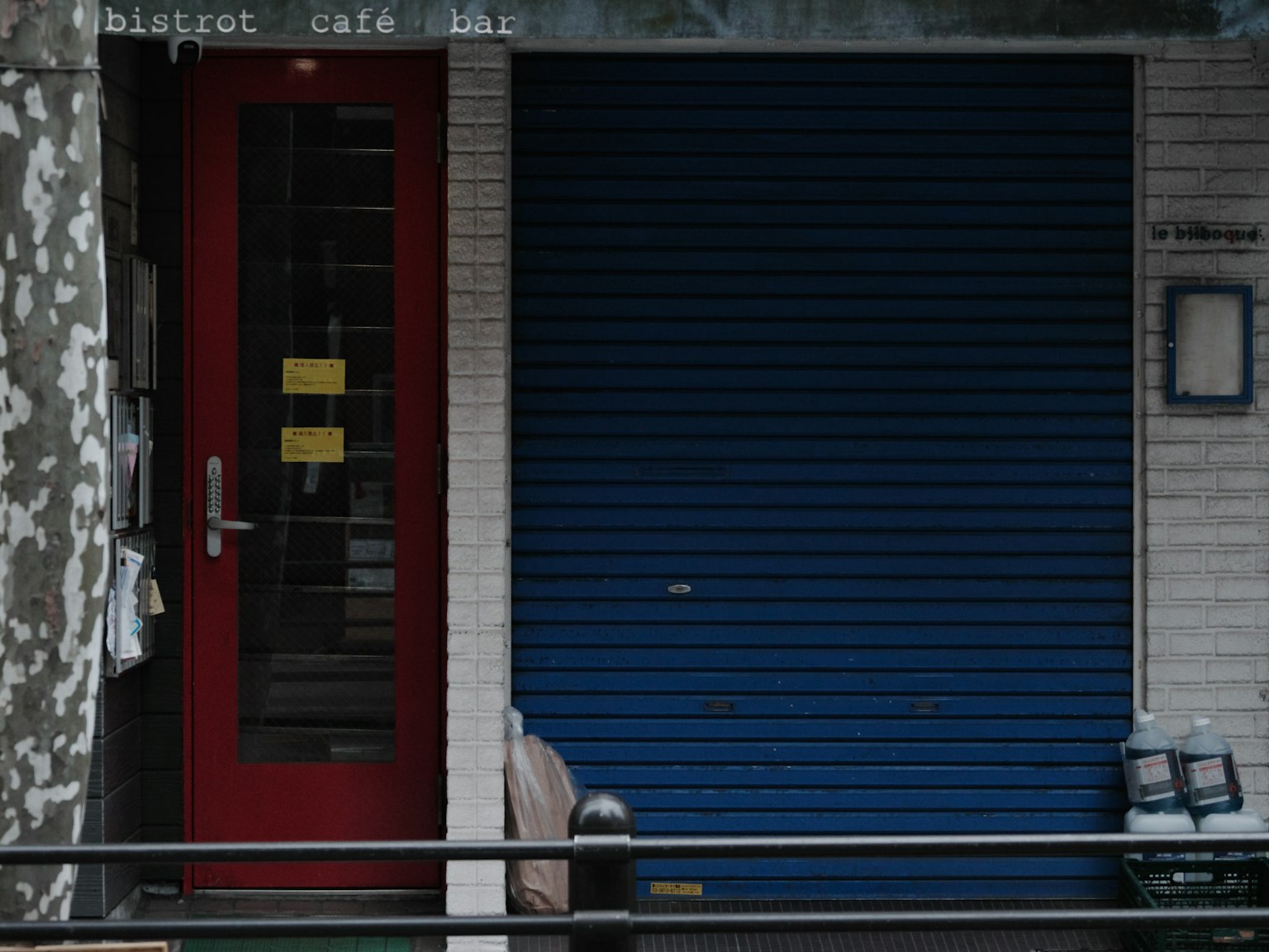 Ingresso di un caffè con porta rossa e serranda blu