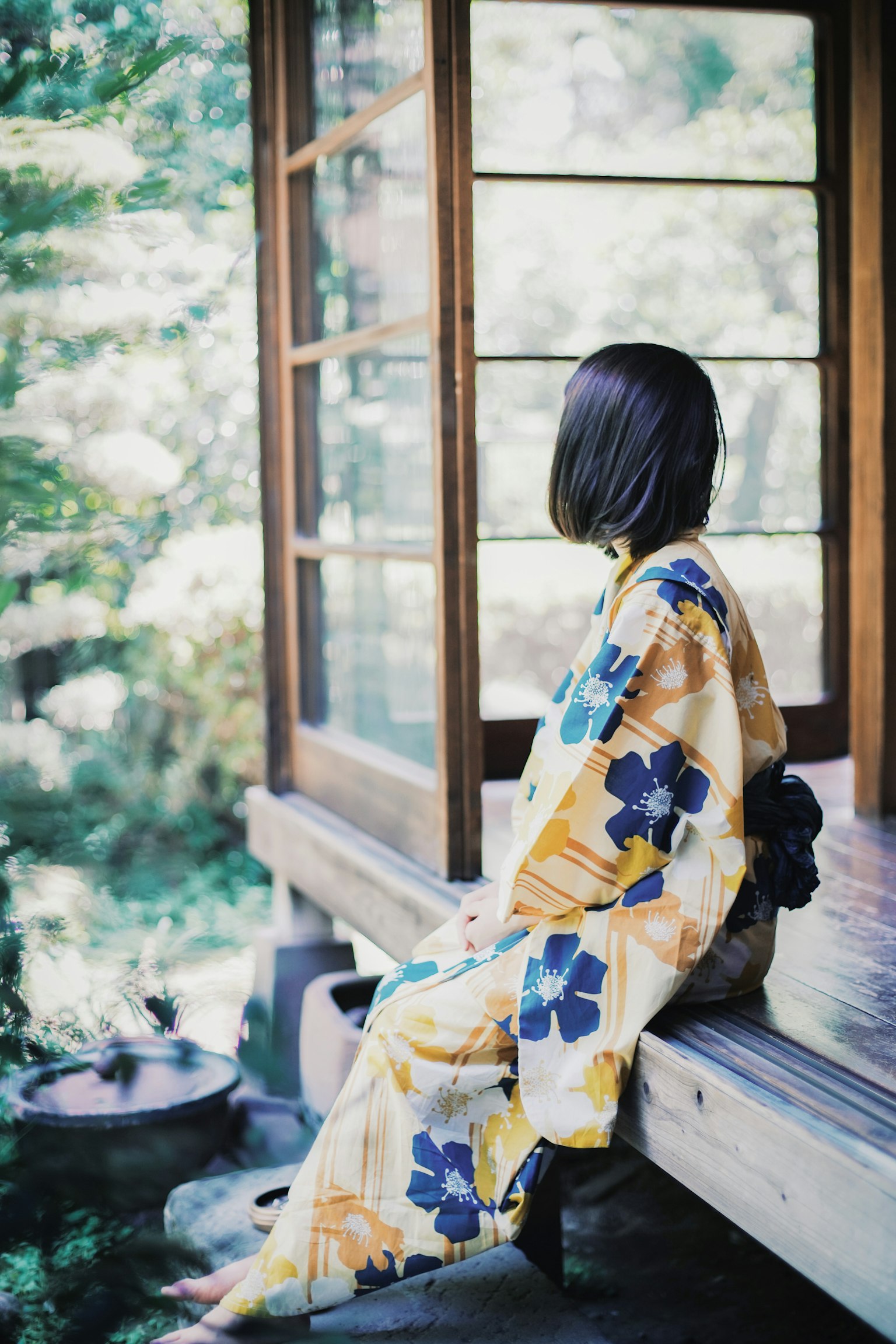 Una donna in kimono seduta fuori di una casa di legno