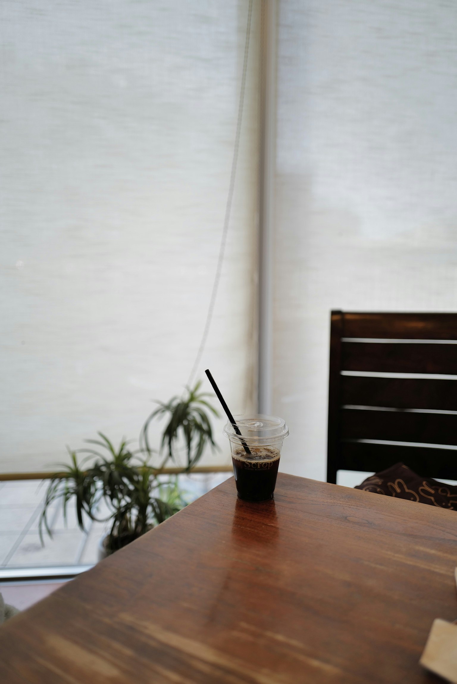 Coin d'un café avec une boisson sur une table en bois et une plante