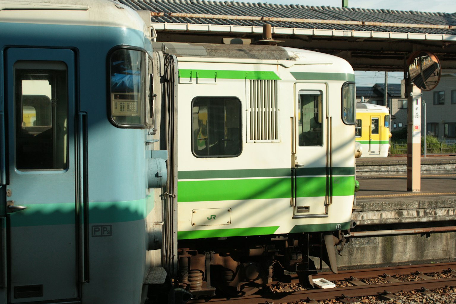 มุมมองด้านข้างของรถไฟที่มีลายสีเขียวและพื้นหลังสถานี