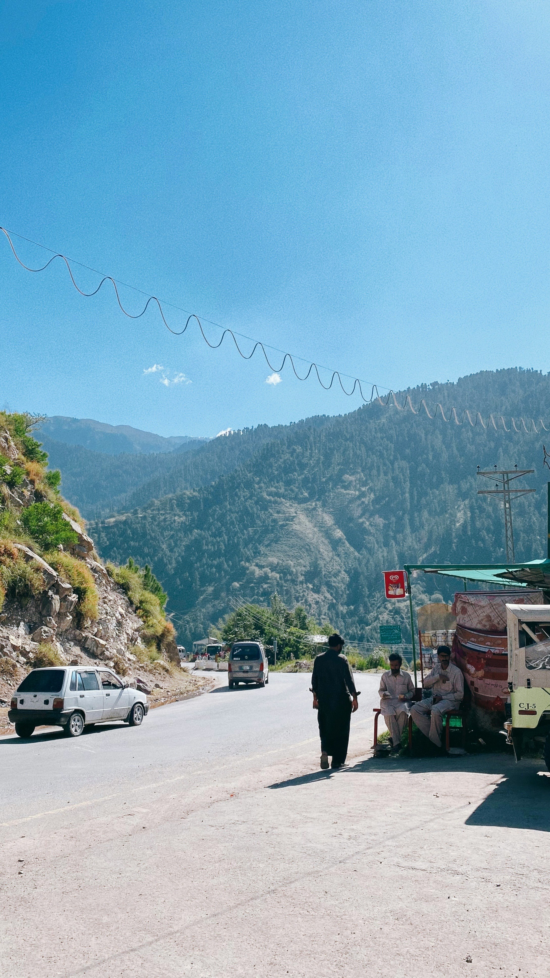 パキスタンのフンザ渓谷の山道で停車する車と人々